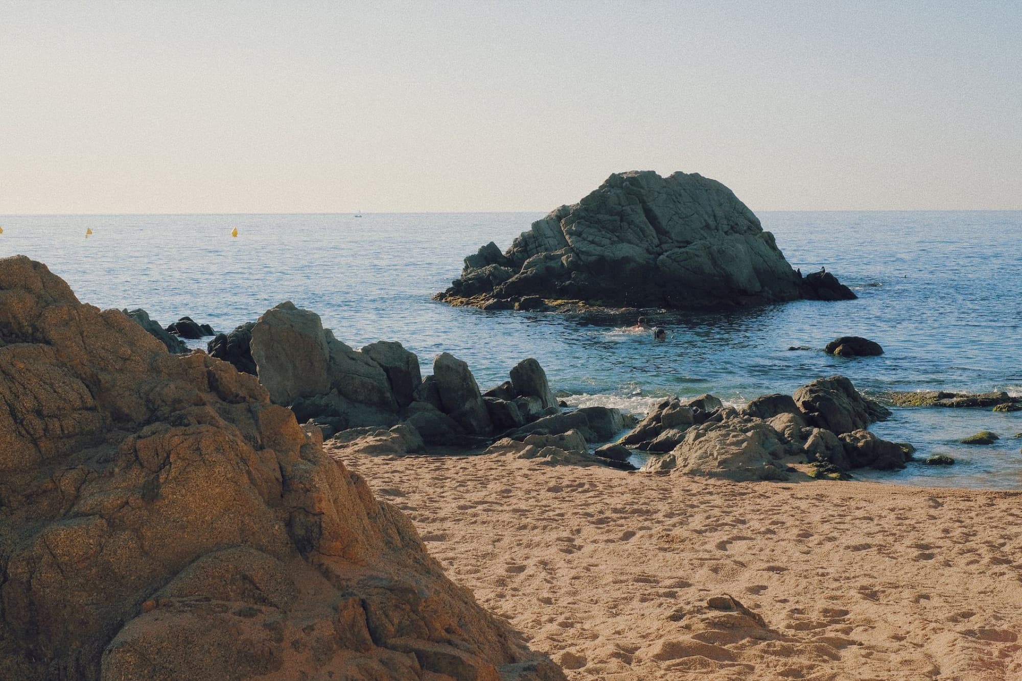 Picturesque beach scene in Costa Brava featuring clear water and prominent rock formations.