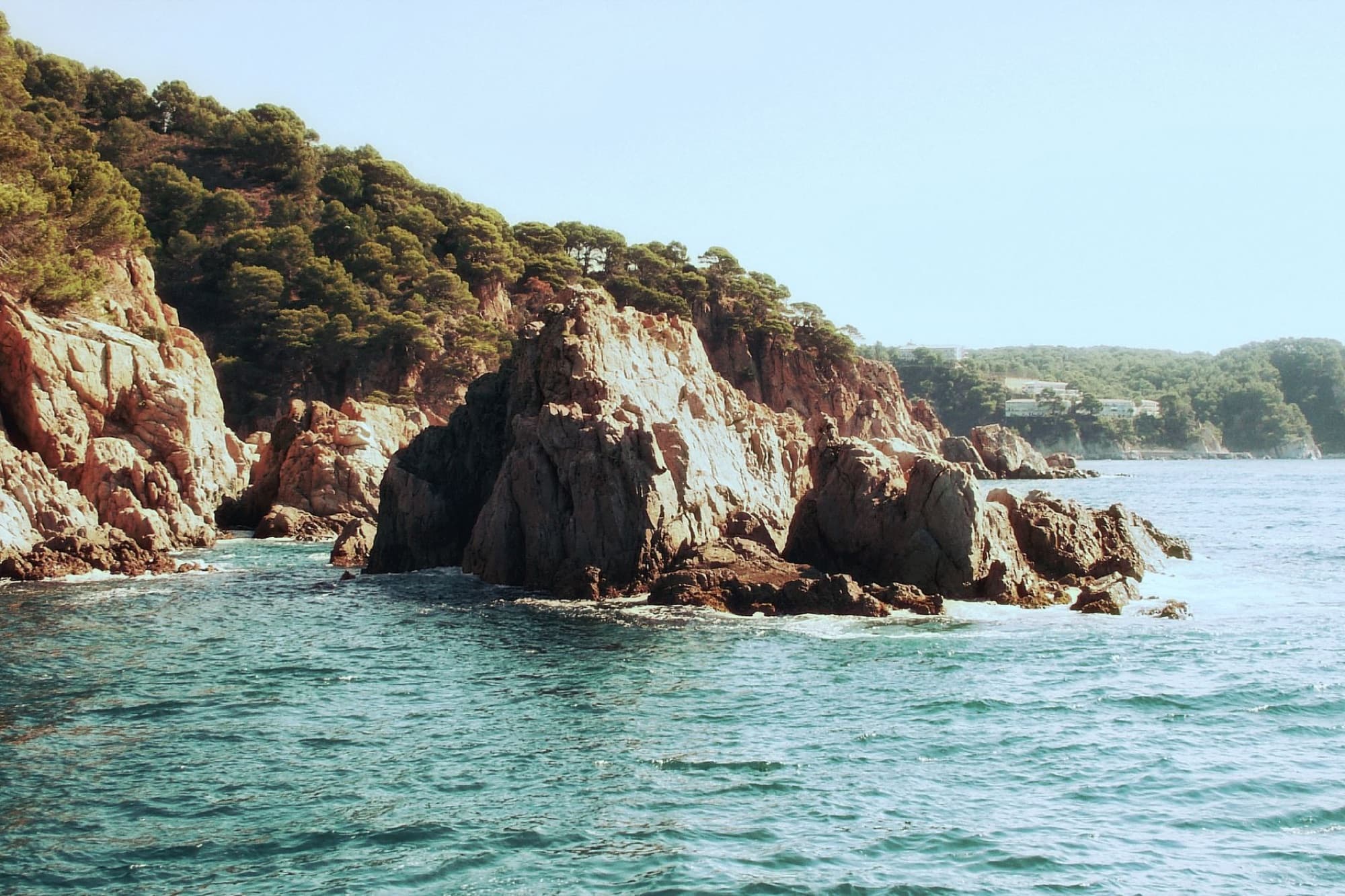 Dramatic rocky cliffs meeting the azure sea in Costa Brava, Spain. Ideal summer escape.