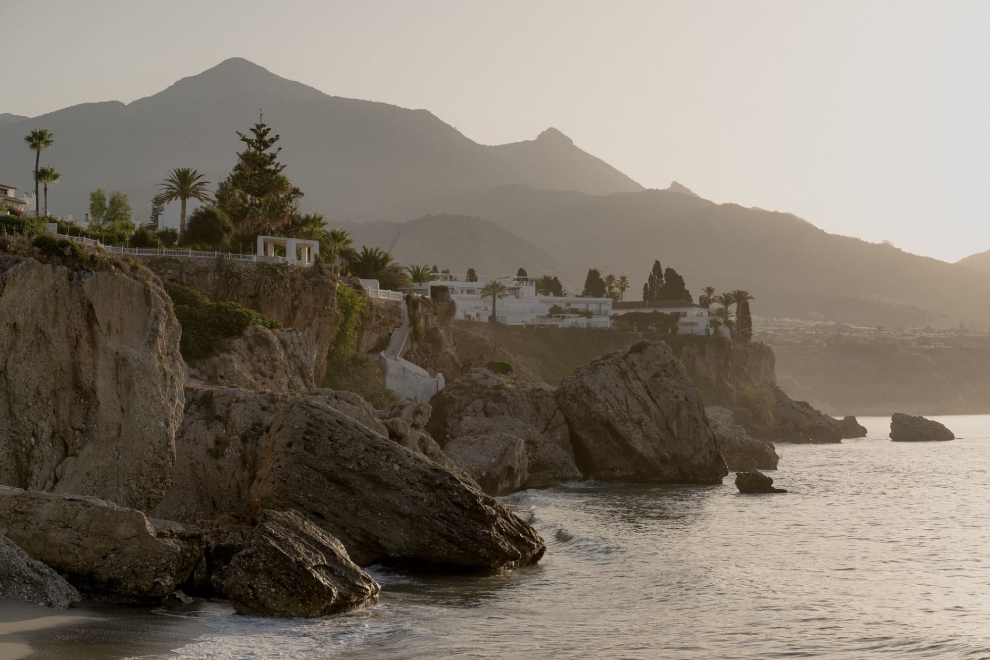 Breathtaking view of coastal cliffs and mountains bathed in sunrise light along the Mediterranean coast.