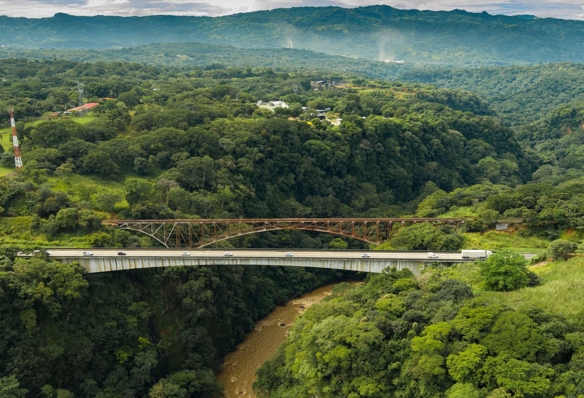 Stunning aerial shot of dual bridges over a river in the green, mountainous valley of Concepción, Costa Rica.