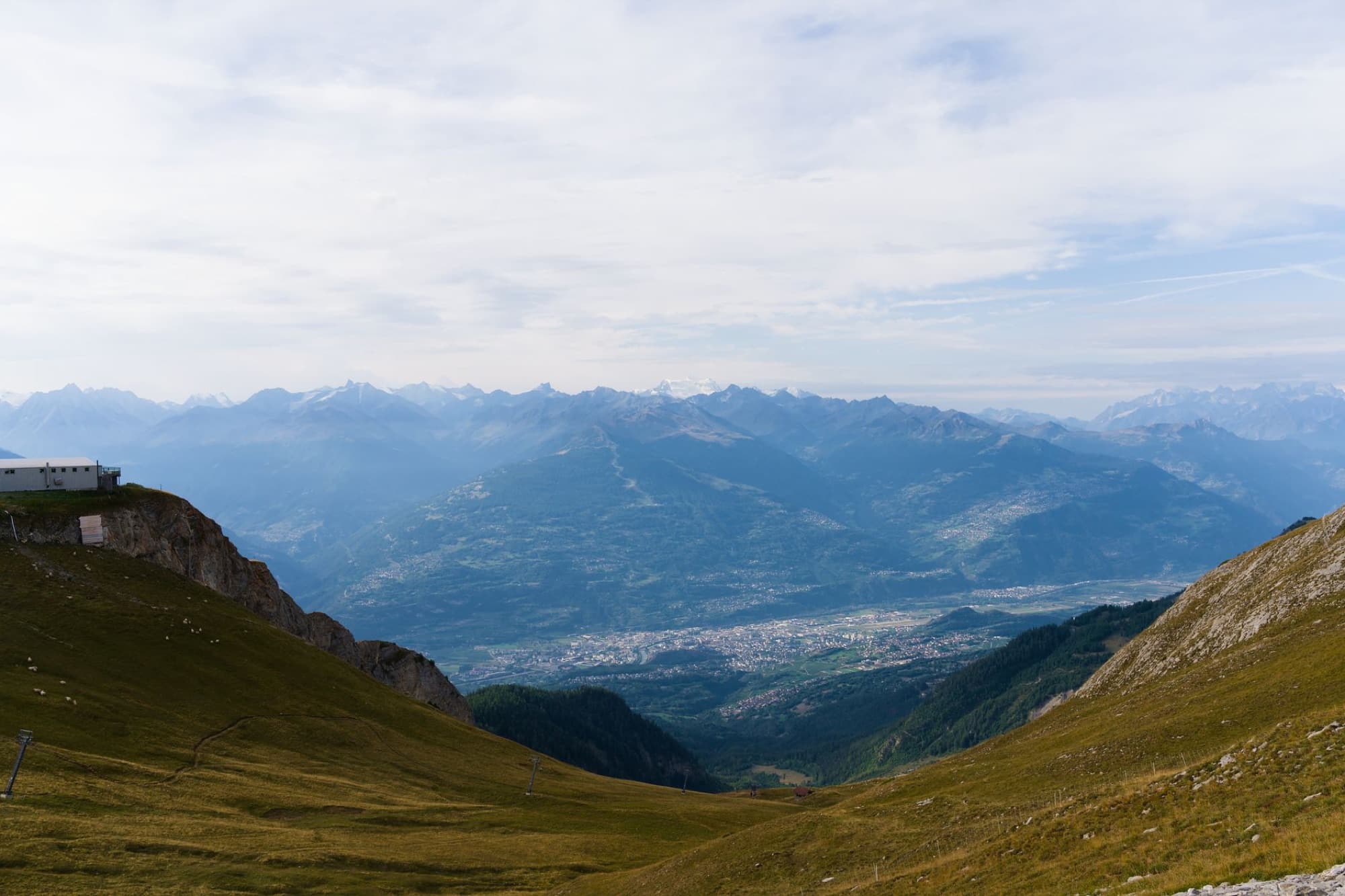 An awe-inspiring landscape of the Swiss Alps as seen from Crans-Montana, showcasing majestic mountains and a serene valley.