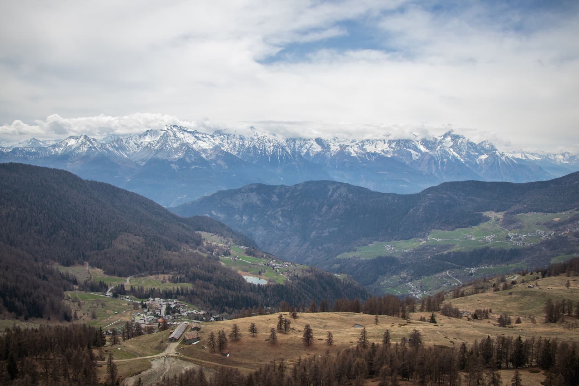 Stunning aerial view of snow-capped mountains and a lush valley creating a breathtaking landscape.