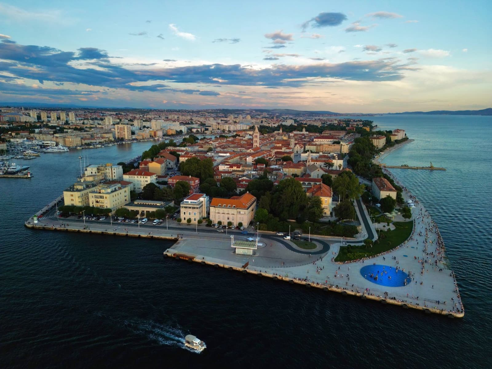 Scenic aerial view of Zadar's peninsula and harbor during sunset with vibrant cityscape and the Adriatic Sea.