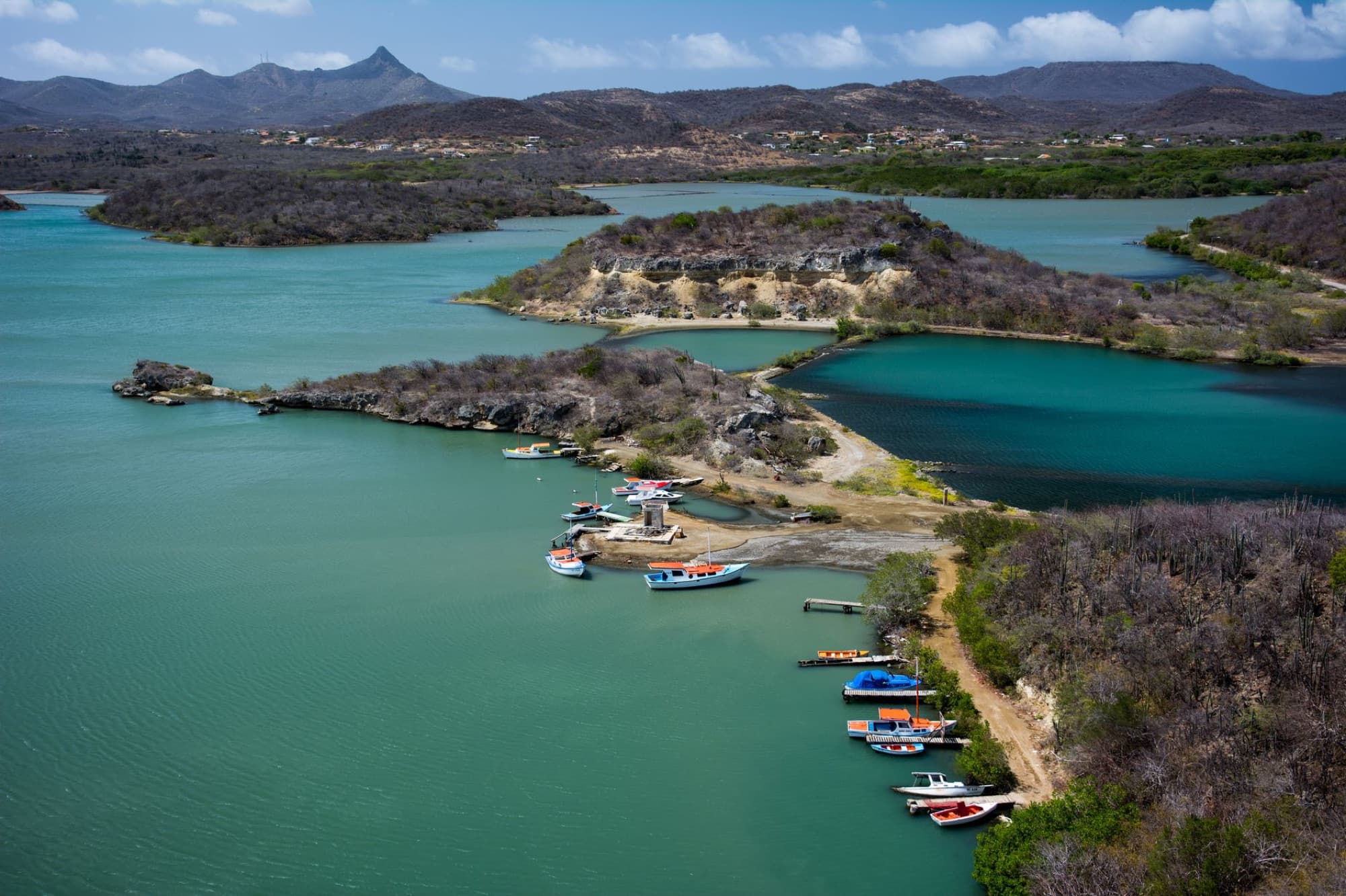 Aerial photograph showcasing a beautiful, turquoise bay in Curacao with boats and scenic hills.