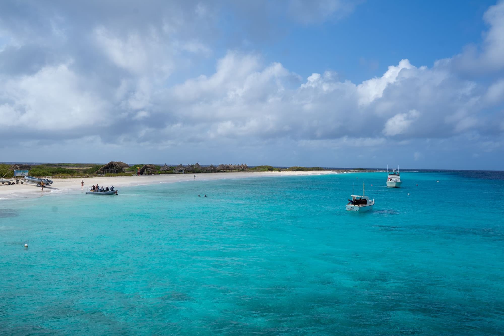 Scenic view of a peaceful beach with turquoise waters and boats in Curaçao, perfect for travel inspiration.
