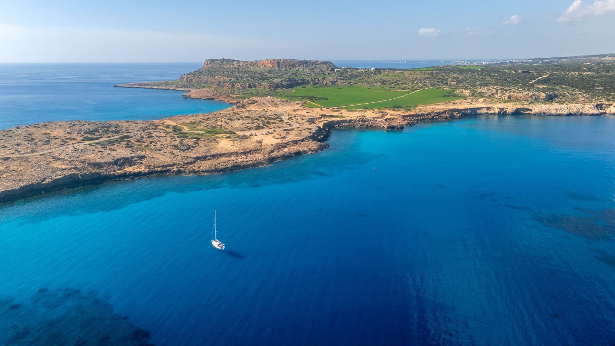 Aerial view of a sailboat on the turquoise waters of Cyprus's scenic coastline.
