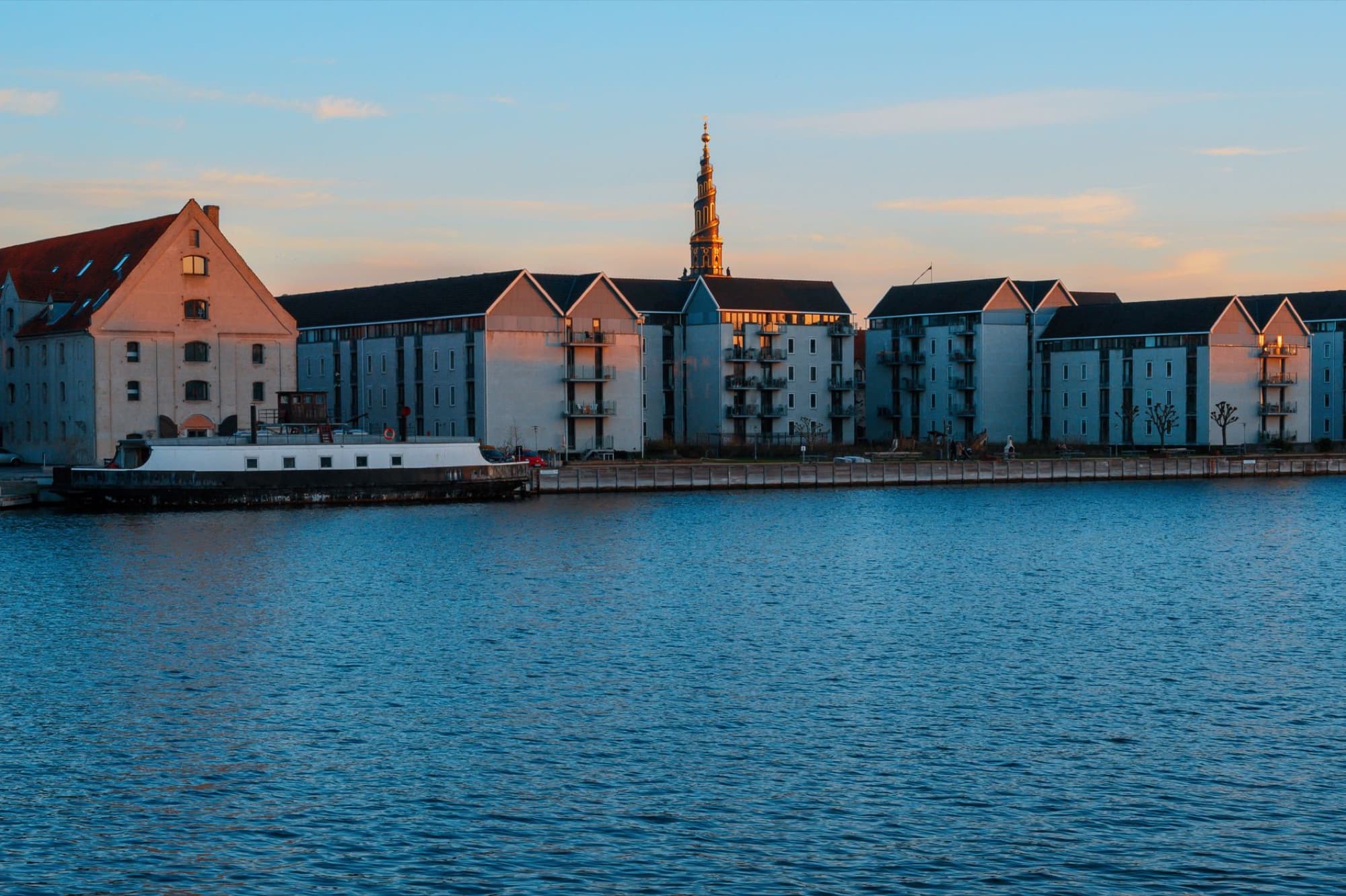 Scenic view of waterfront residential buildings in Copenhagen, Denmark during sunset.