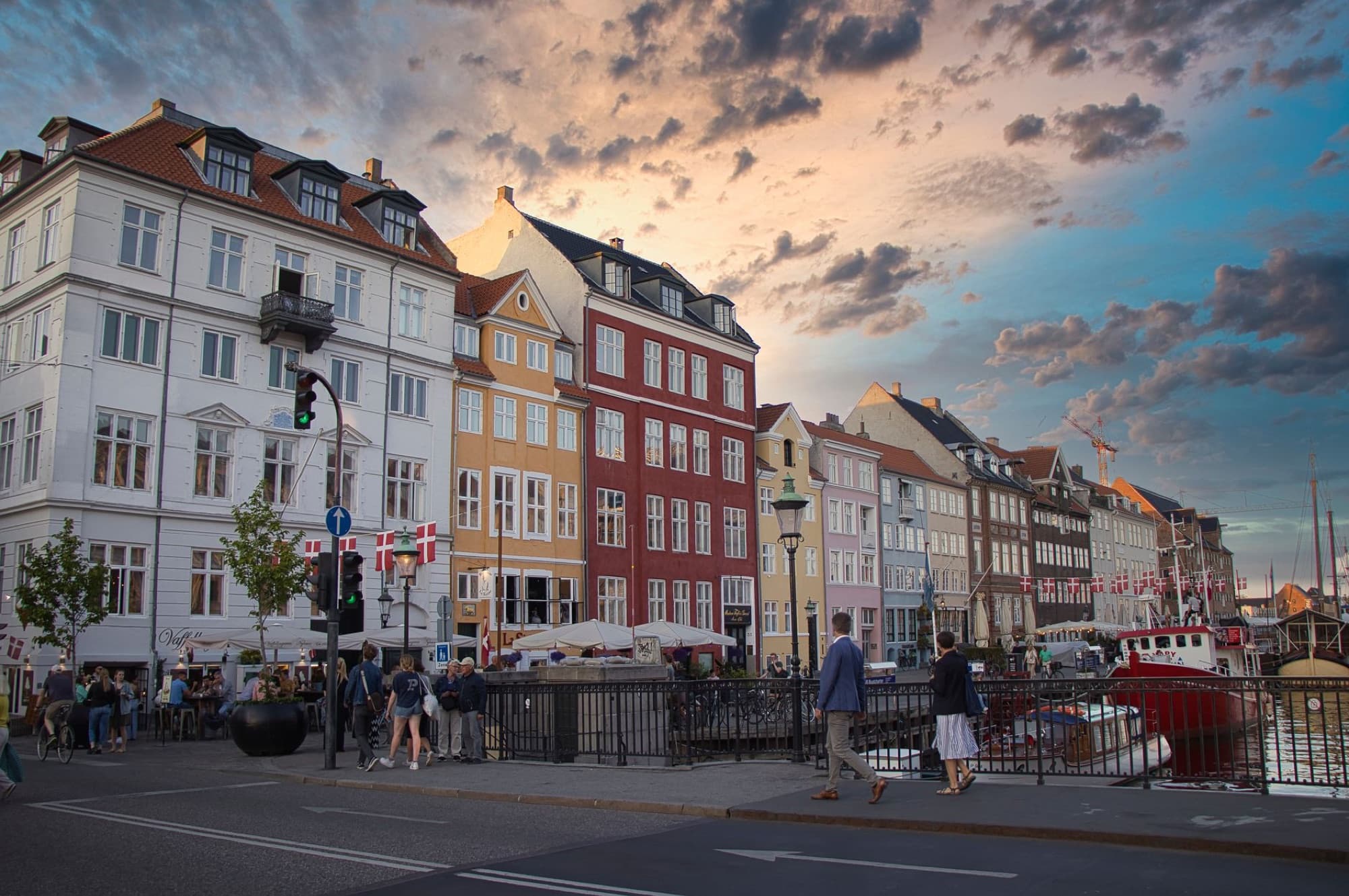 Scenic view of Nyhavn's colorful buildings and vibrant urban life during dusk in Copenhagen, Denmark.