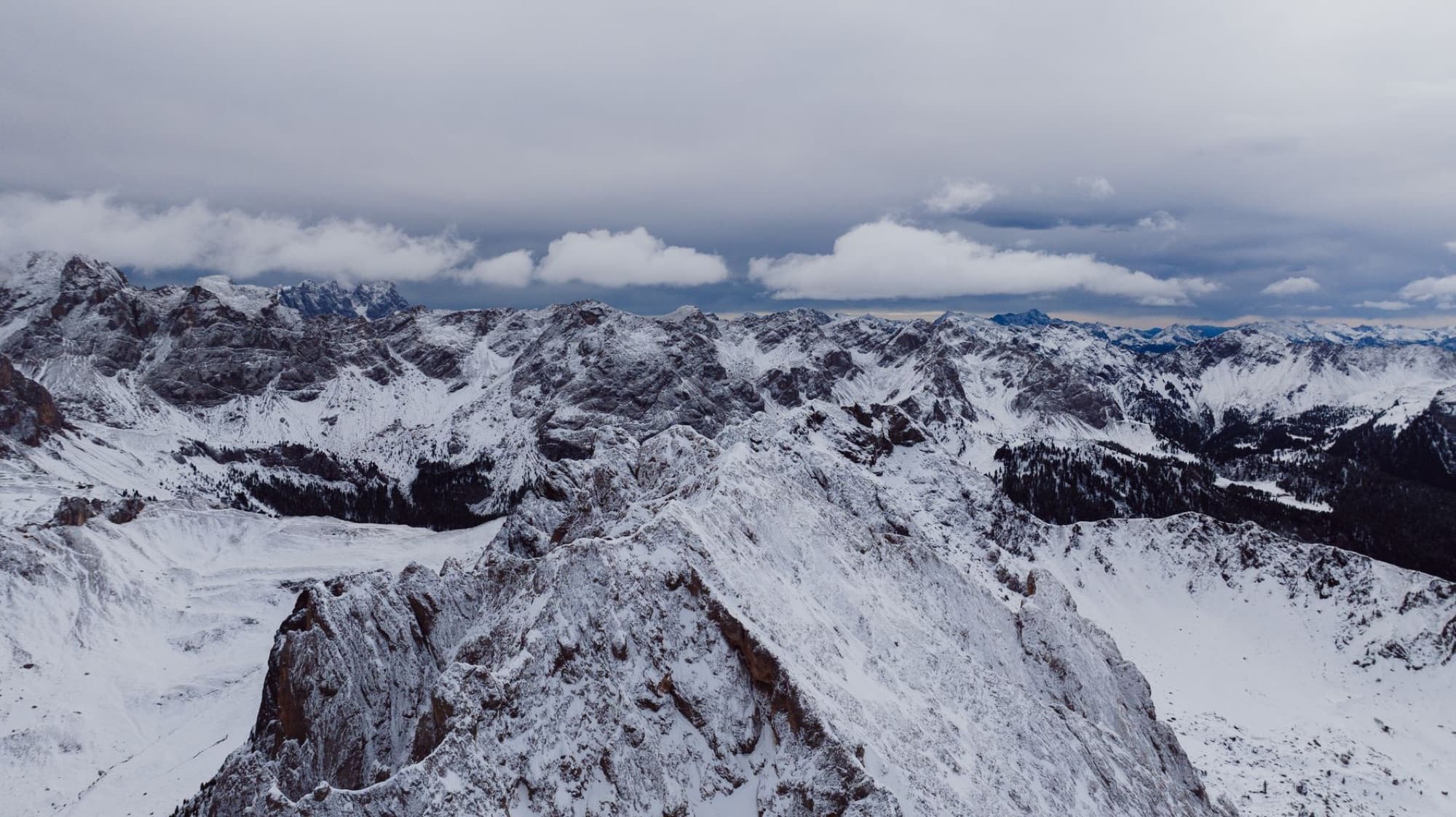 Scenic winter aerial of the snow-covered Dolomites in Canazei, Italy, showcasing rugged peaks.