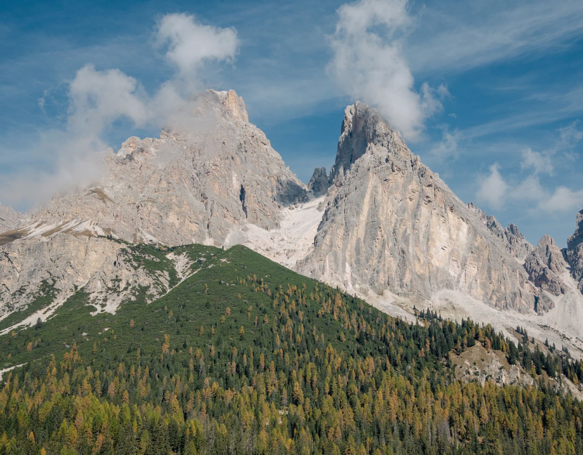 Stunning Dolomites landscape with rugged peaks and forested slopes under a clear sky.
