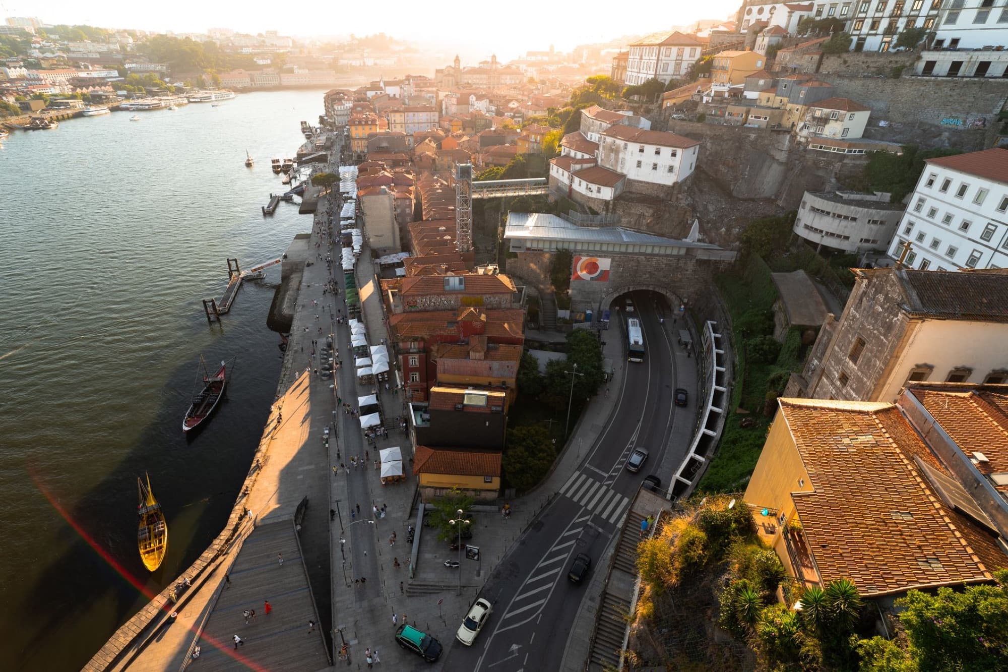 Scenic aerial view of Porto, Portugal, featuring the Douro River, traditional buildings, and roads at sunset.