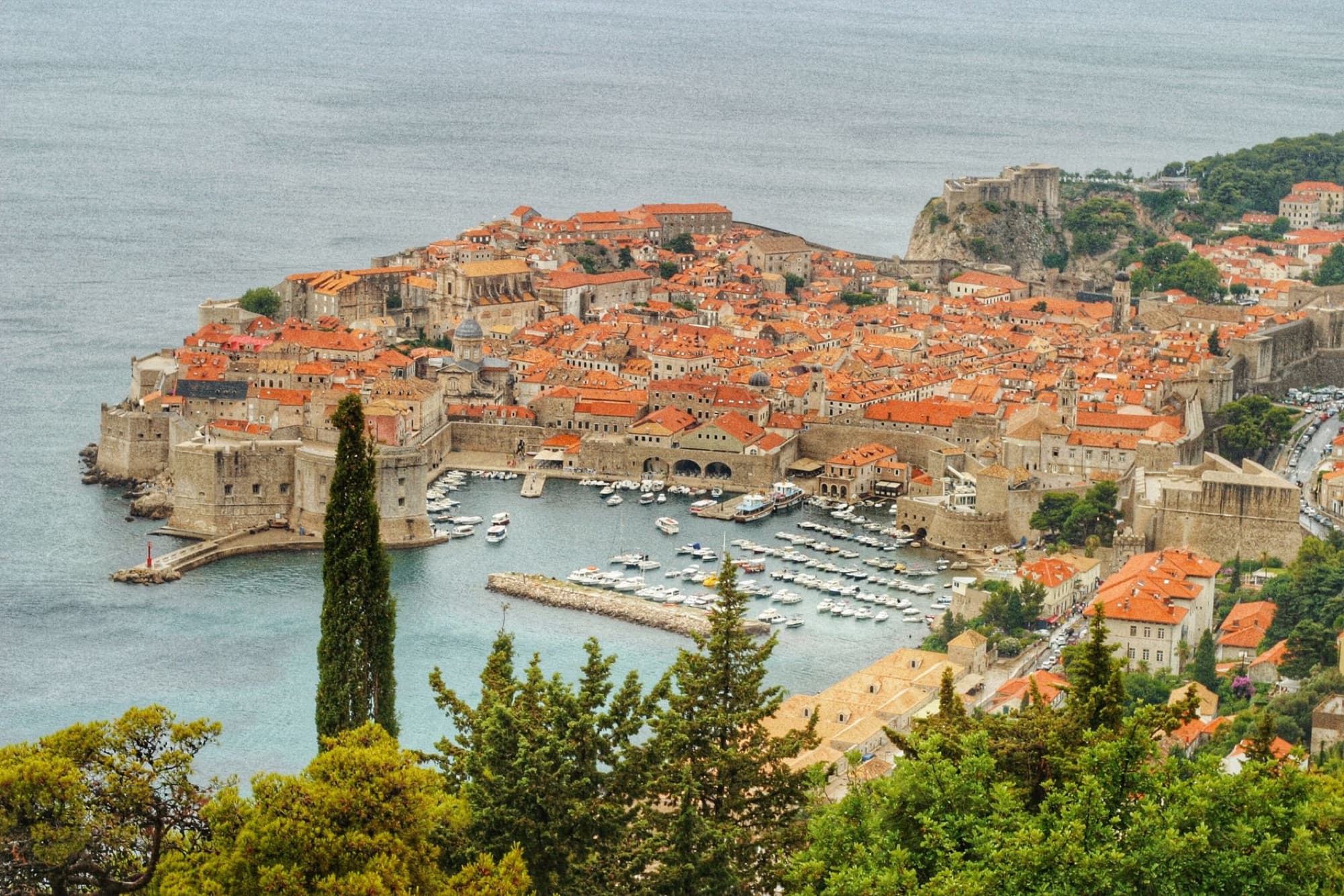 Explore the stunning aerial view of Dubrovnik's historic old town and harbor with majestic city walls.