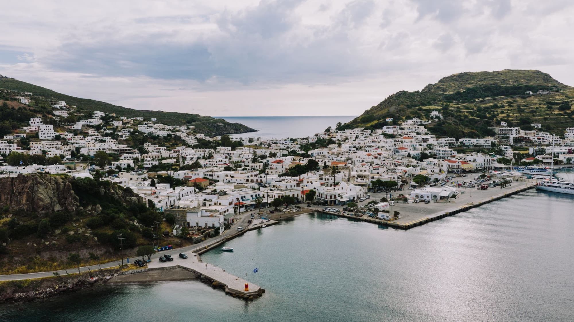 Explore the stunning harbor and traditional white buildings of Patmos Island, Greece, with this captivating aerial view.