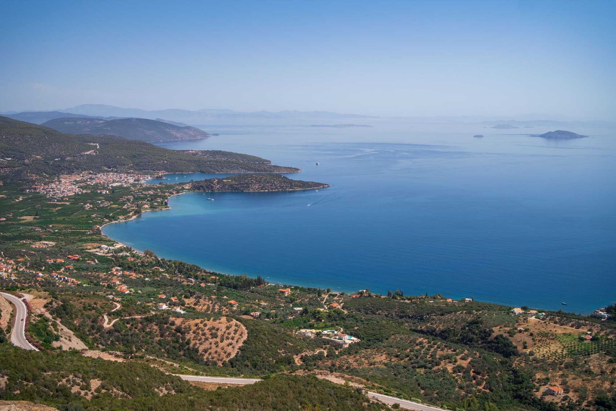 Breathtaking aerial shot of the Greek coastline with clear blue waters and lush landscape.