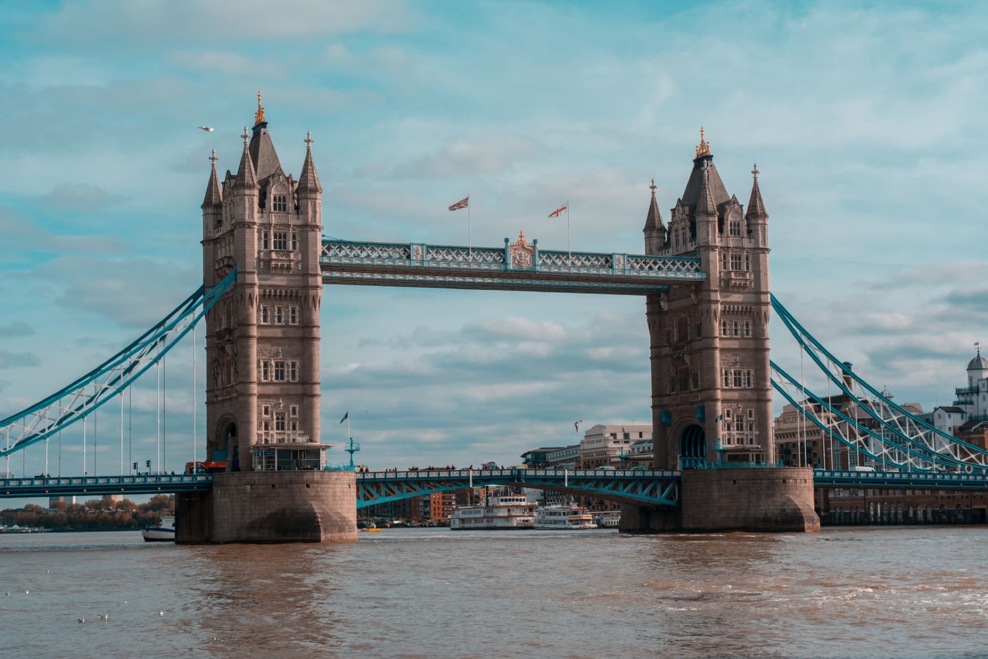 Capture of the iconic Tower Bridge spanning the River Thames in London, England, under a cloudy sky.