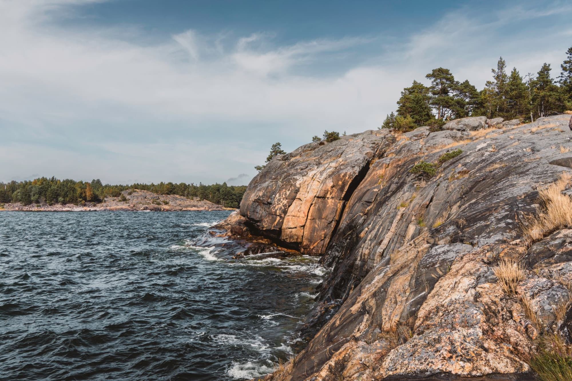 Scenic view of rugged cliffs and sea in Porkkala Peninsula, Finland, under a cloudy sky.