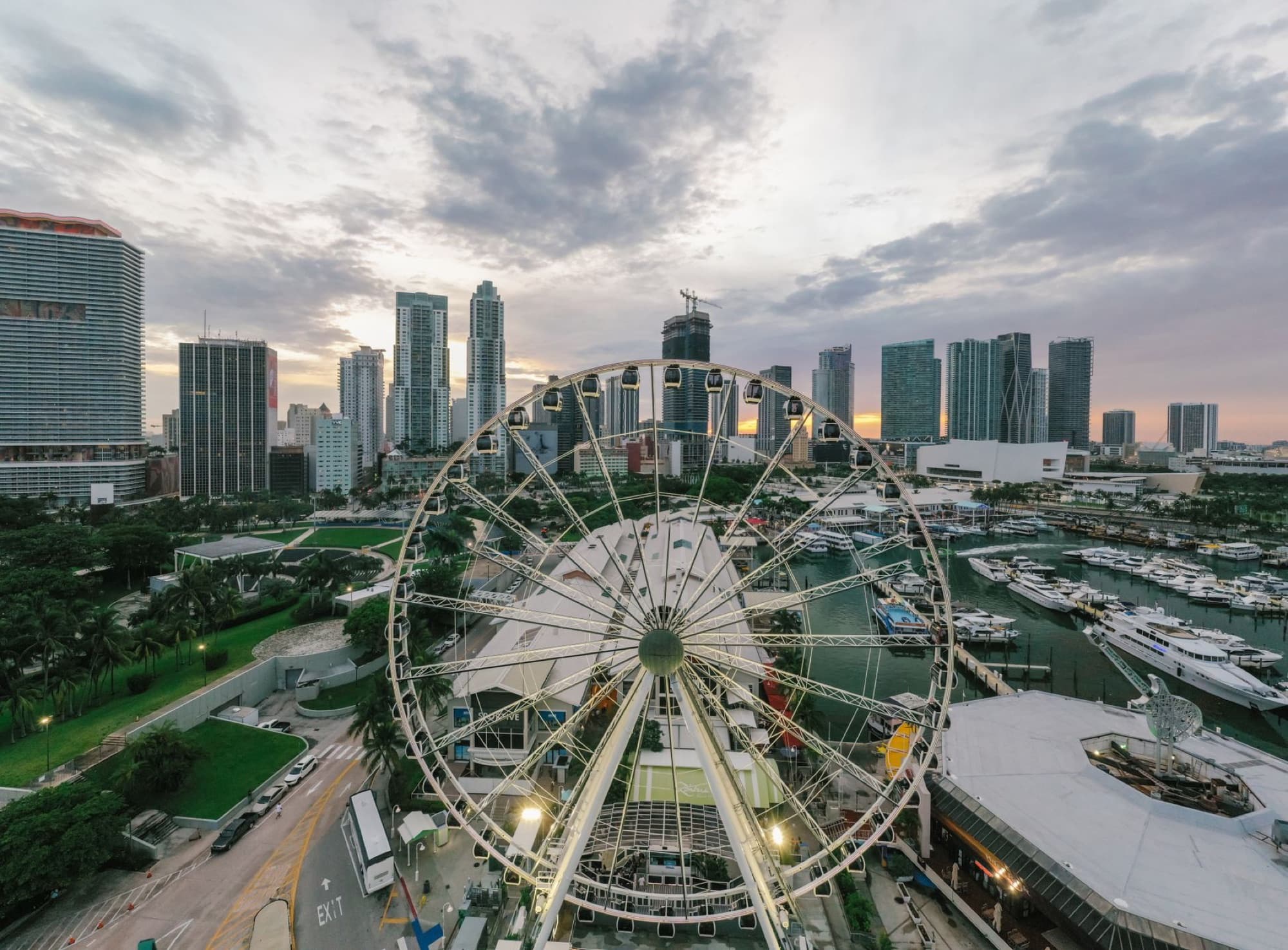 A breathtaking aerial view of Miami featuring a ferris wheel against the city skyline and harbor at sunset.
