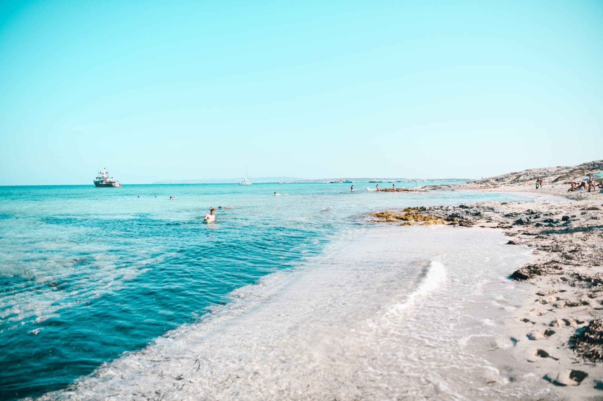 Relaxing beach scene in Formentera, Spain with clear blue waters and a serene horizon.
