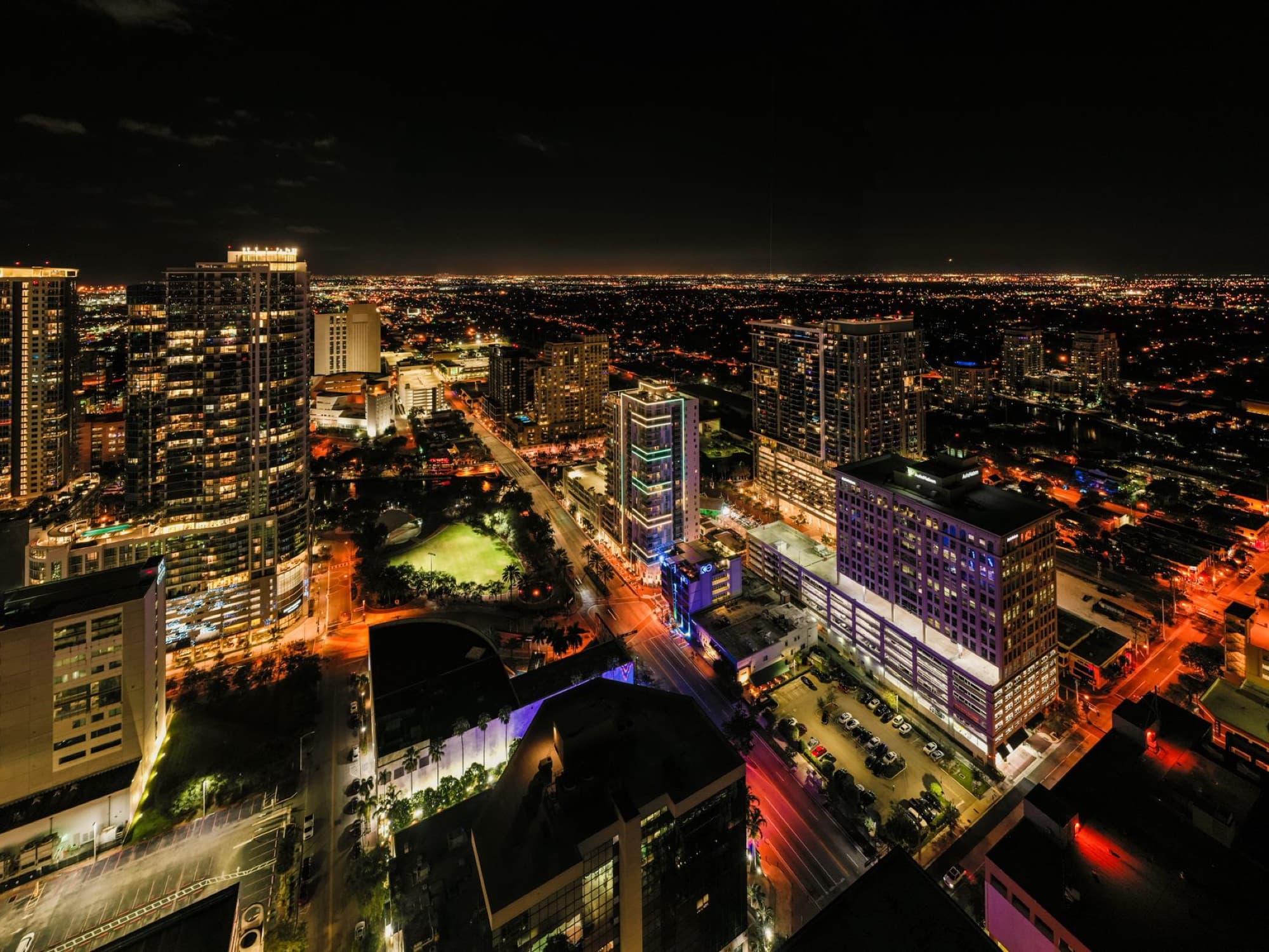 Breathtaking drone view of modern Fort Lauderdale city district with illuminated street and skyscrapers against dark night sky