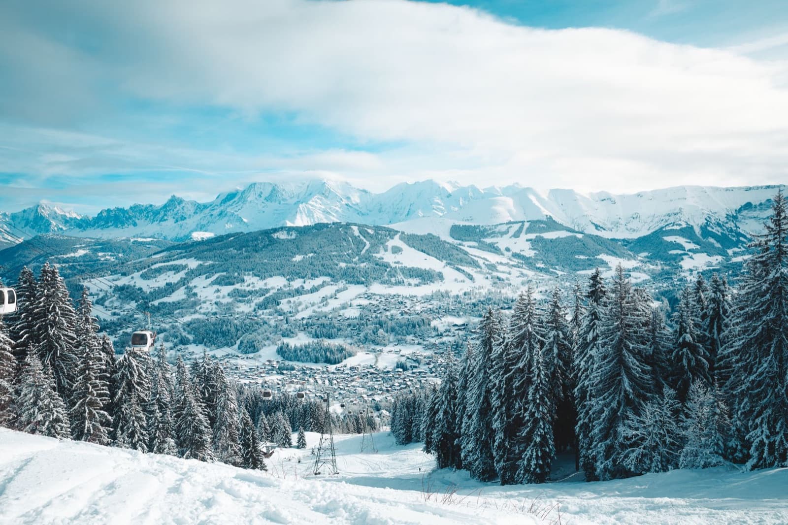 Captivating winter landscape of Megève, France, showcasing snow-covered mountains and a peaceful forest.