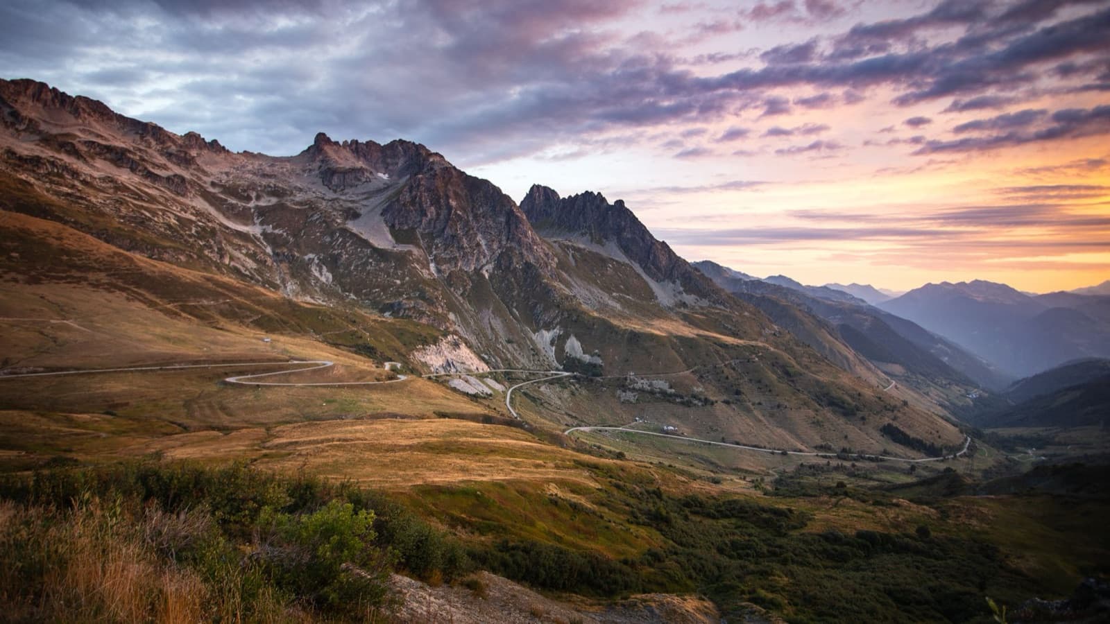 Stunning sunrise over a scenic mountain landscape with winding roads and vibrant colors.
