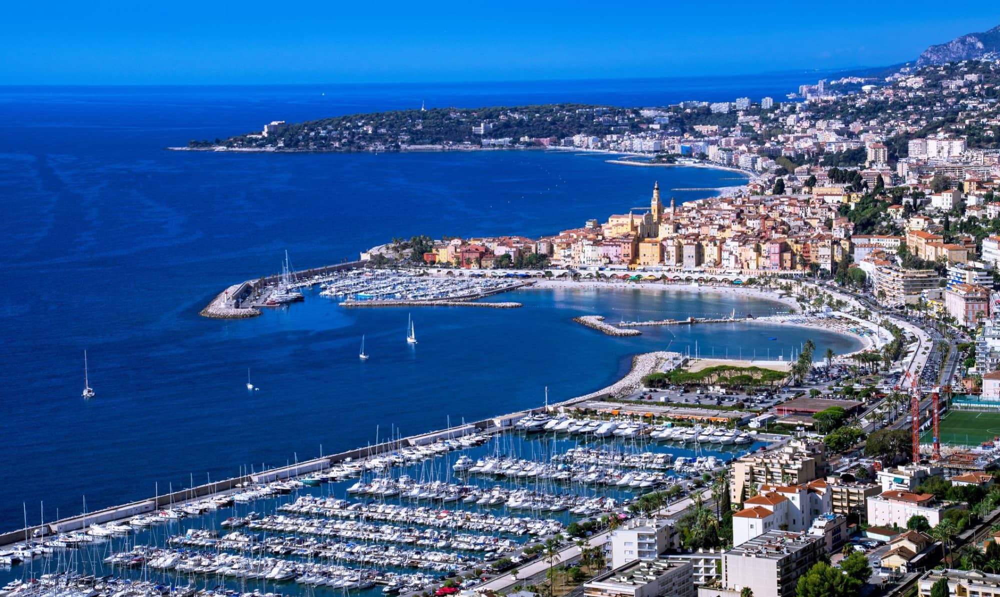 Explore the stunning aerial view of Menton with vibrant architecture along the French Riviera's coastline.