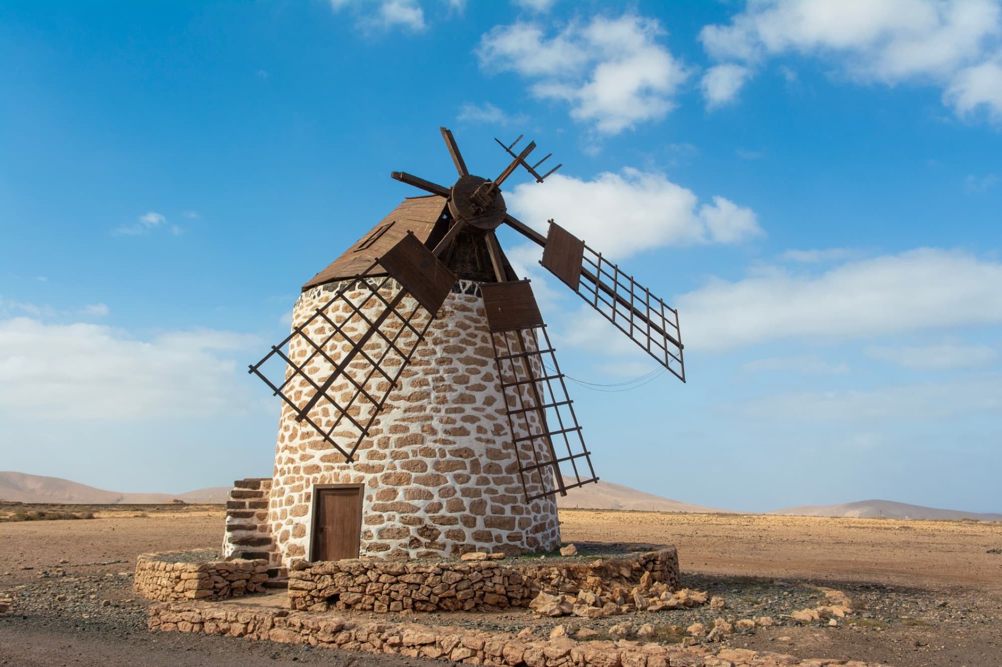 Rustic windmill in the open landscape of Fuerteventura, Spain, under a clear blue sky.