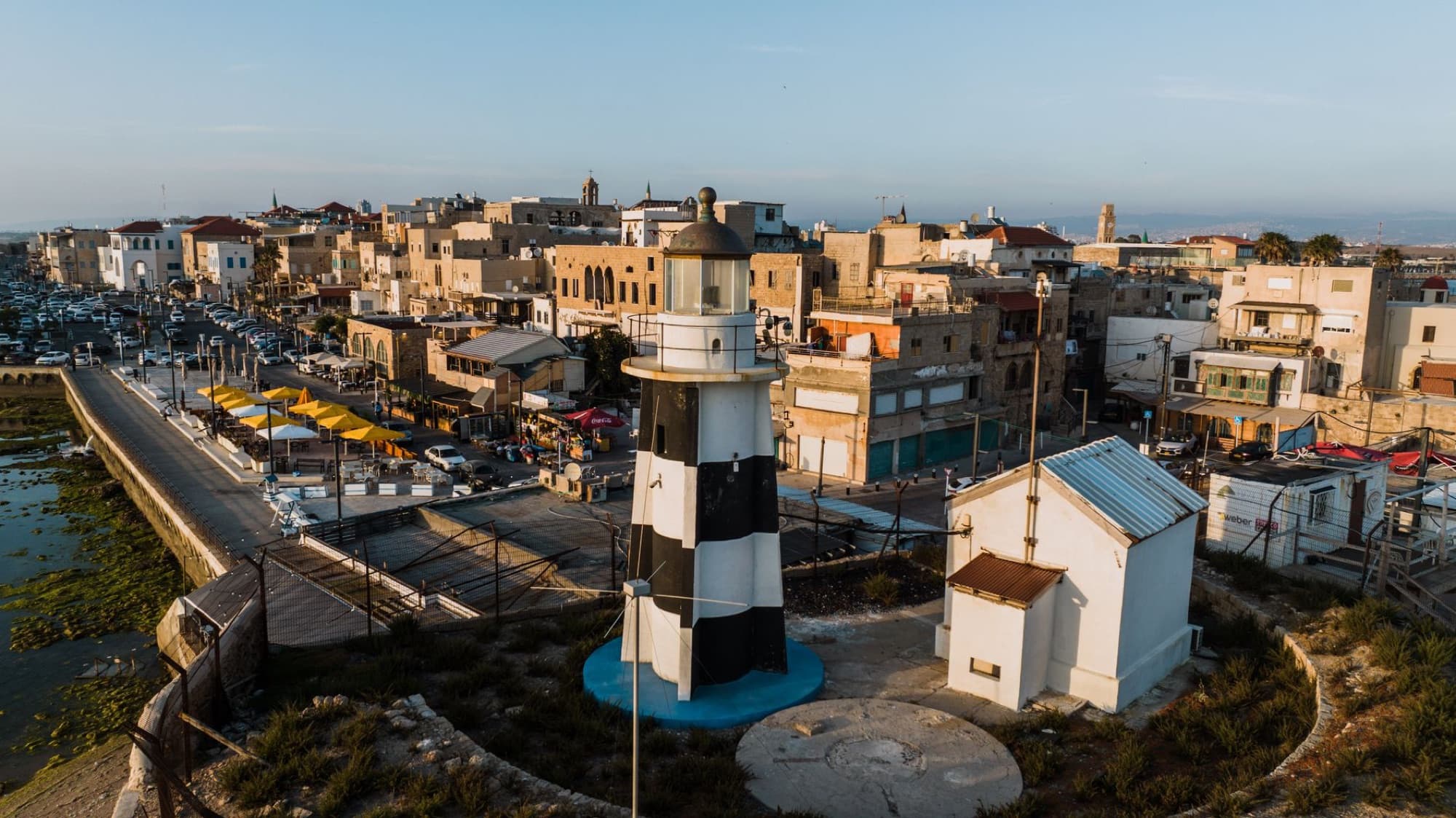 Charming aerial shot of Acre's historic lighthouse and old town, showcasing urban and coastal beauty in Israel.