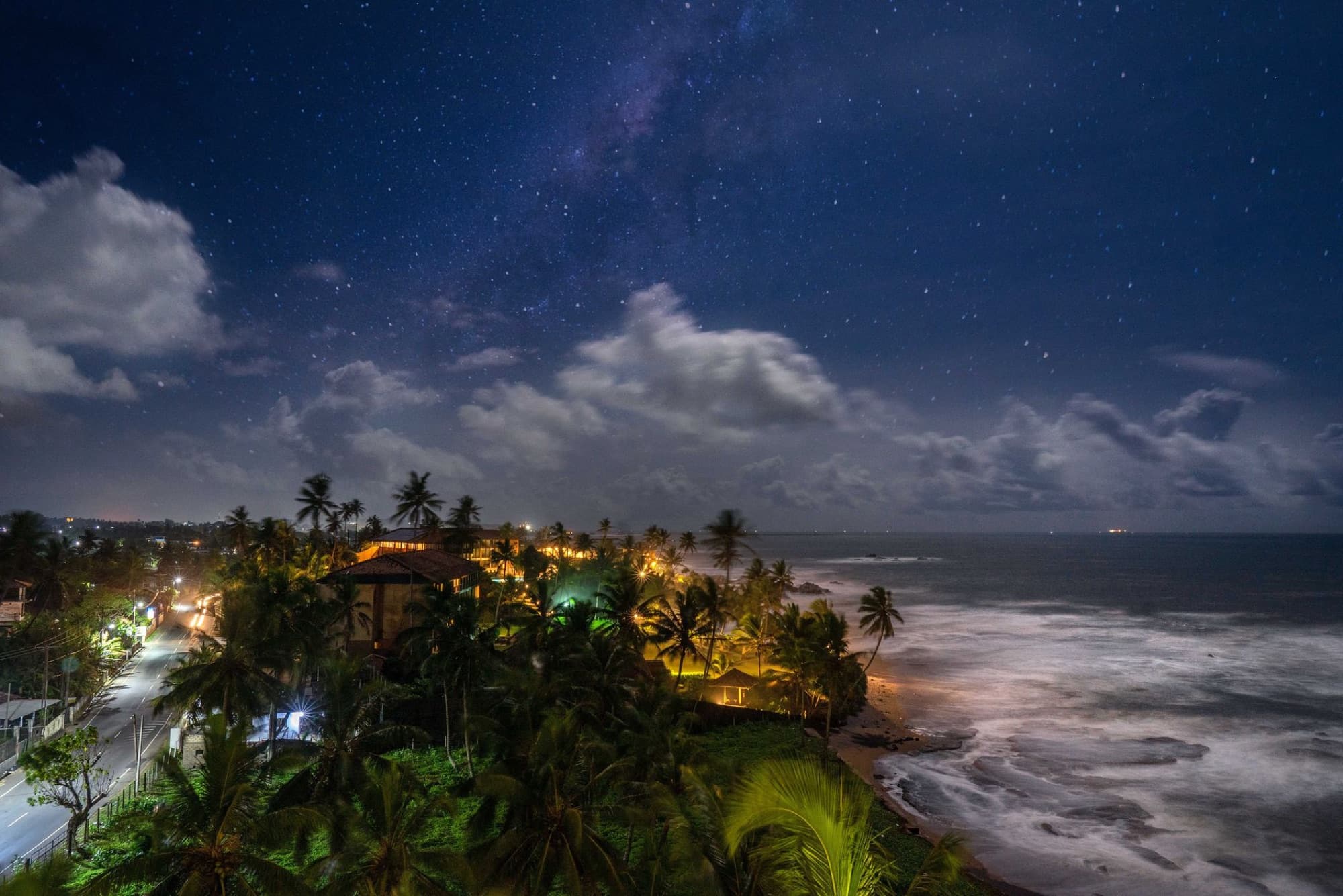 A mesmerizing aerial view of Galle's coastline under a starry night sky with palm trees and ocean waves.