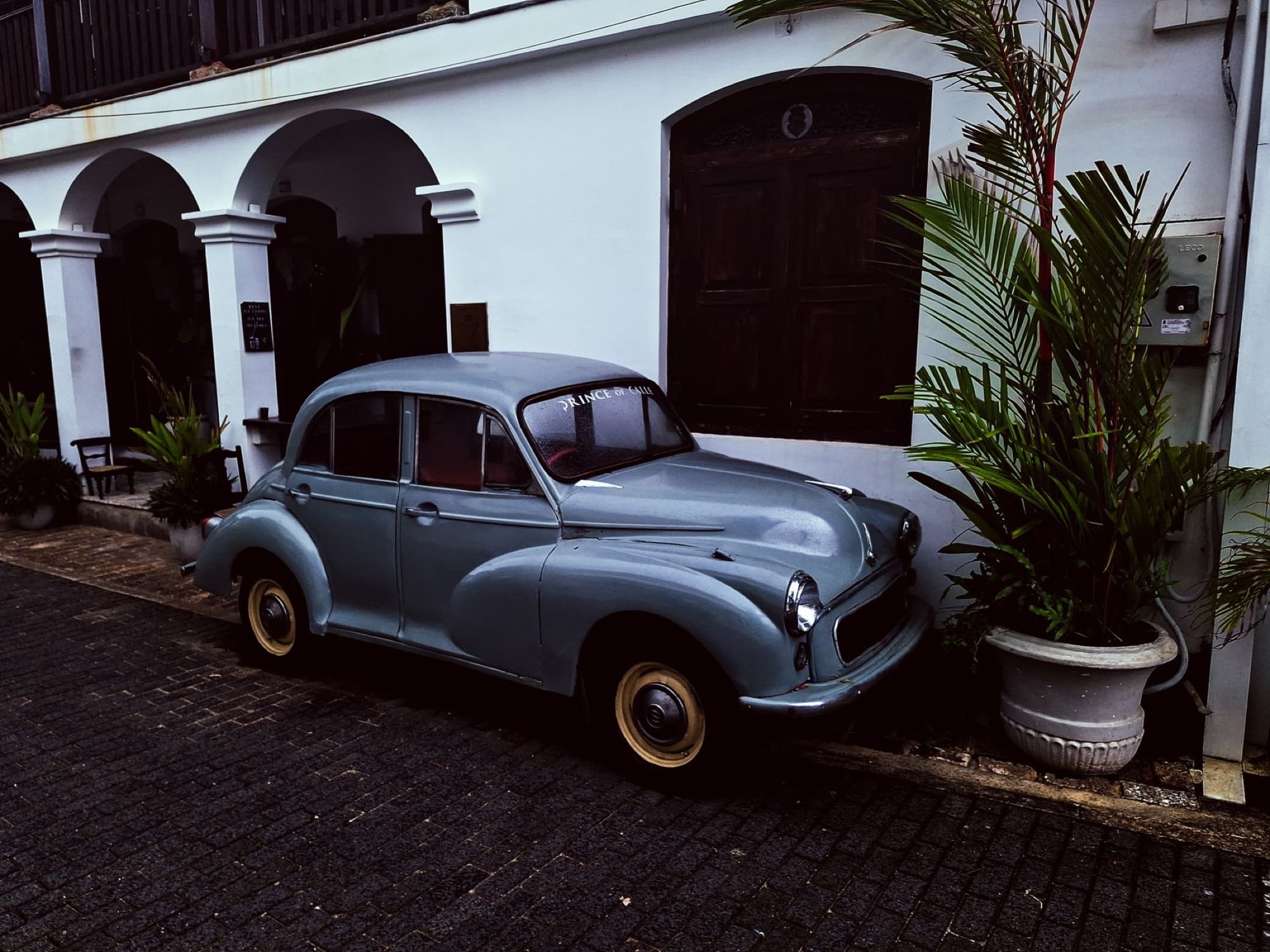 Classic vintage car on a cobblestone street in Galle, Sri Lanka with tropical plants.