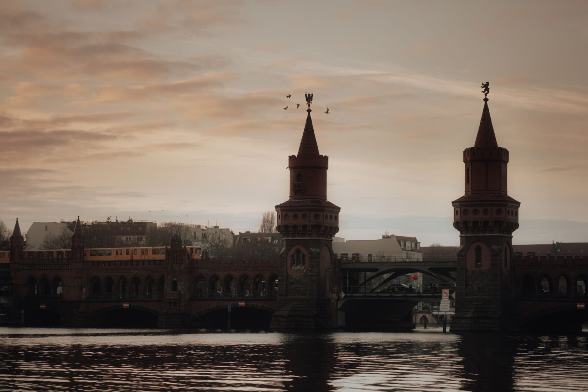 Oberbaum Bridge during sunset with a train passing in Berlin, Germany.