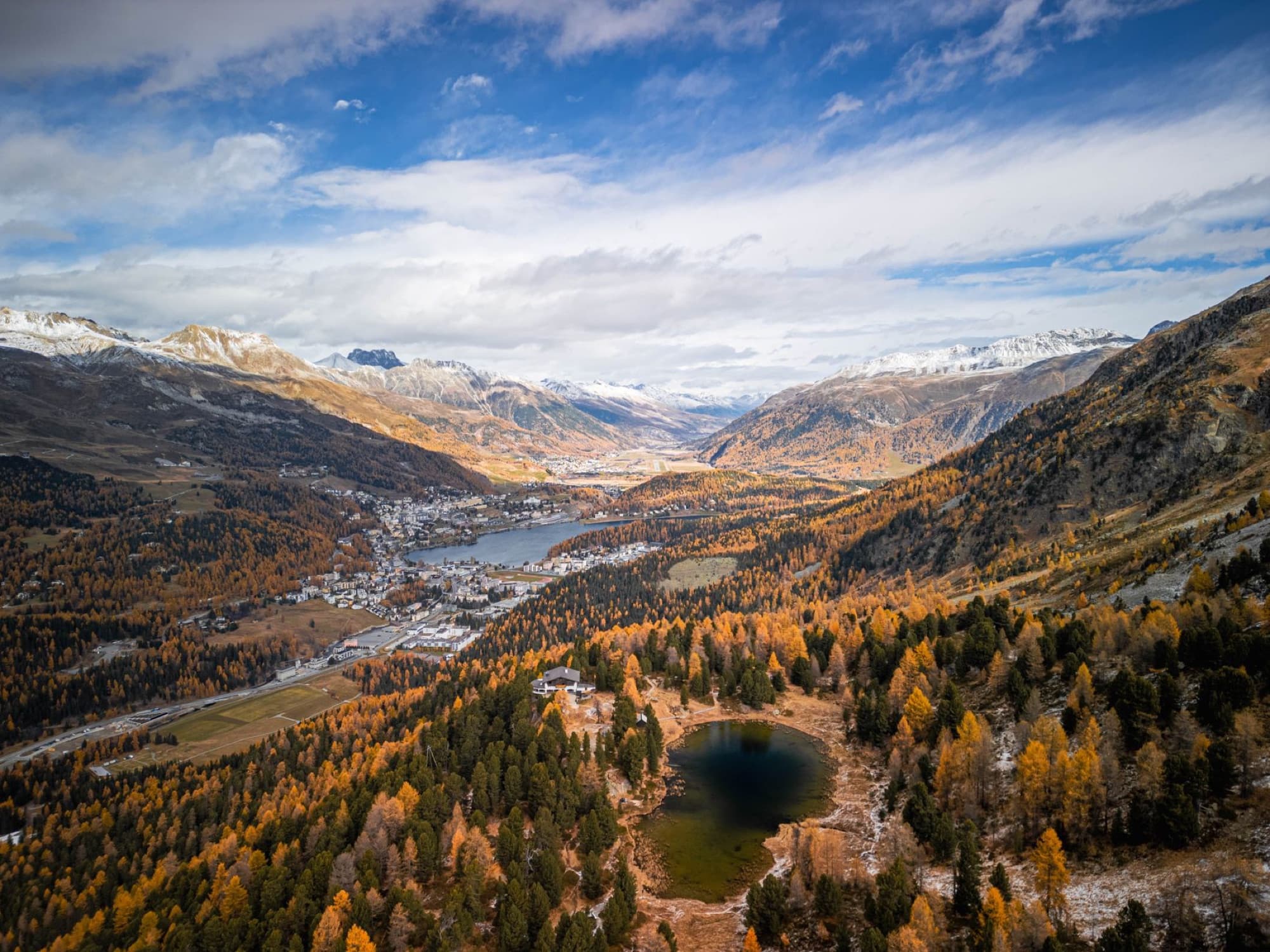 Aerial view of Graubünden's autumn landscape with alpine mountains and forests.