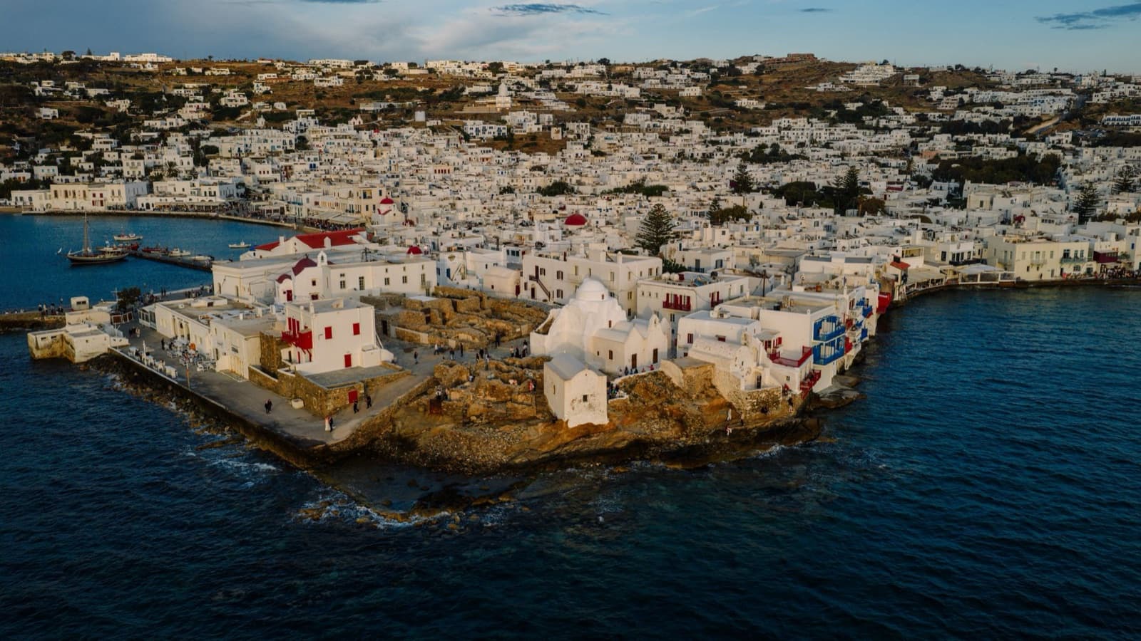 Stunning aerial view of Mykonos town with whitewashed buildings and blue sea, showcasing Greek island architecture.