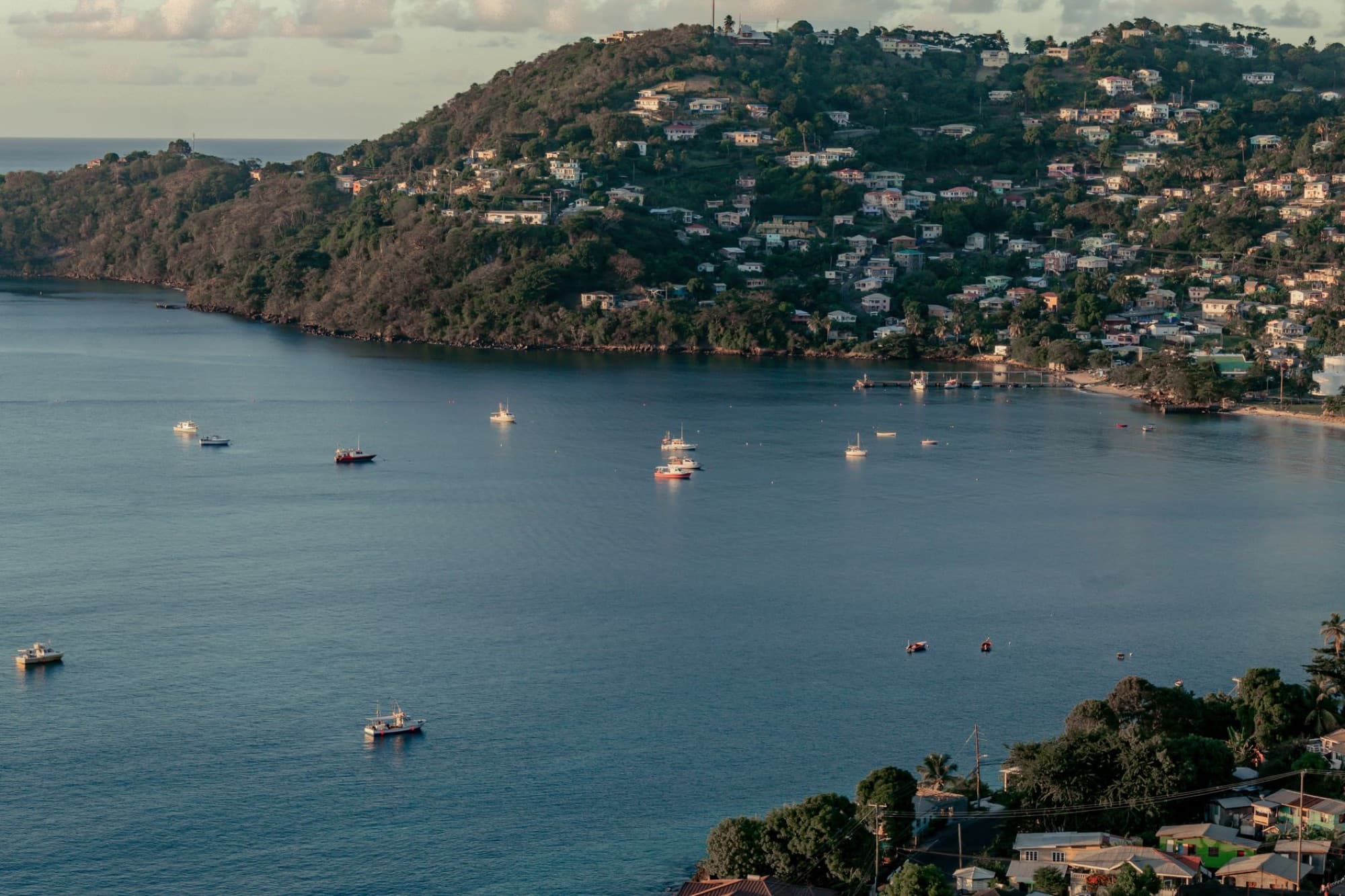 Scenic aerial view of a bay in Grenada with scattered boats and lush hills.