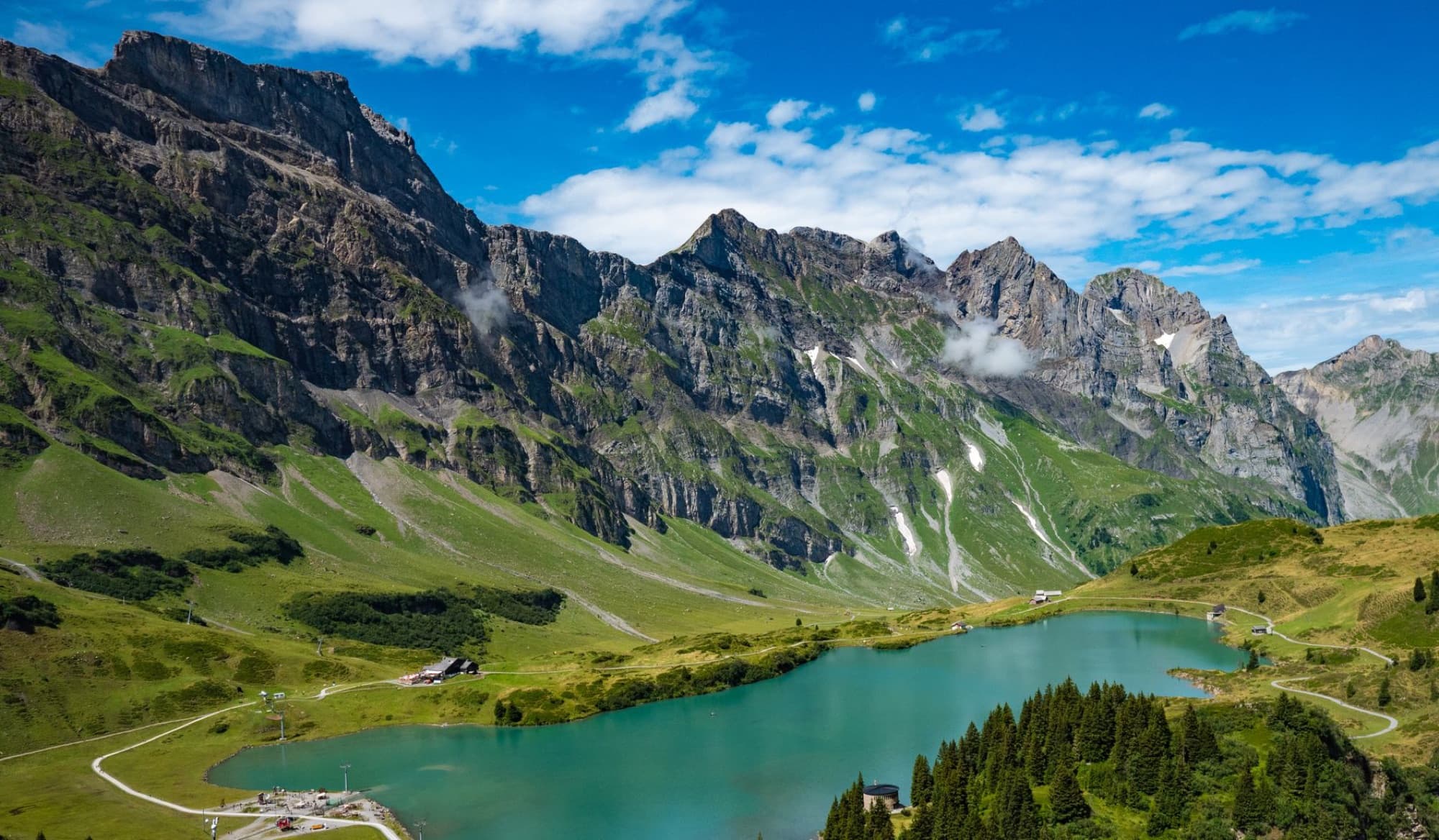 A stunning aerial view of the Swiss Alps featuring a serene blue lake and lush green landscape.