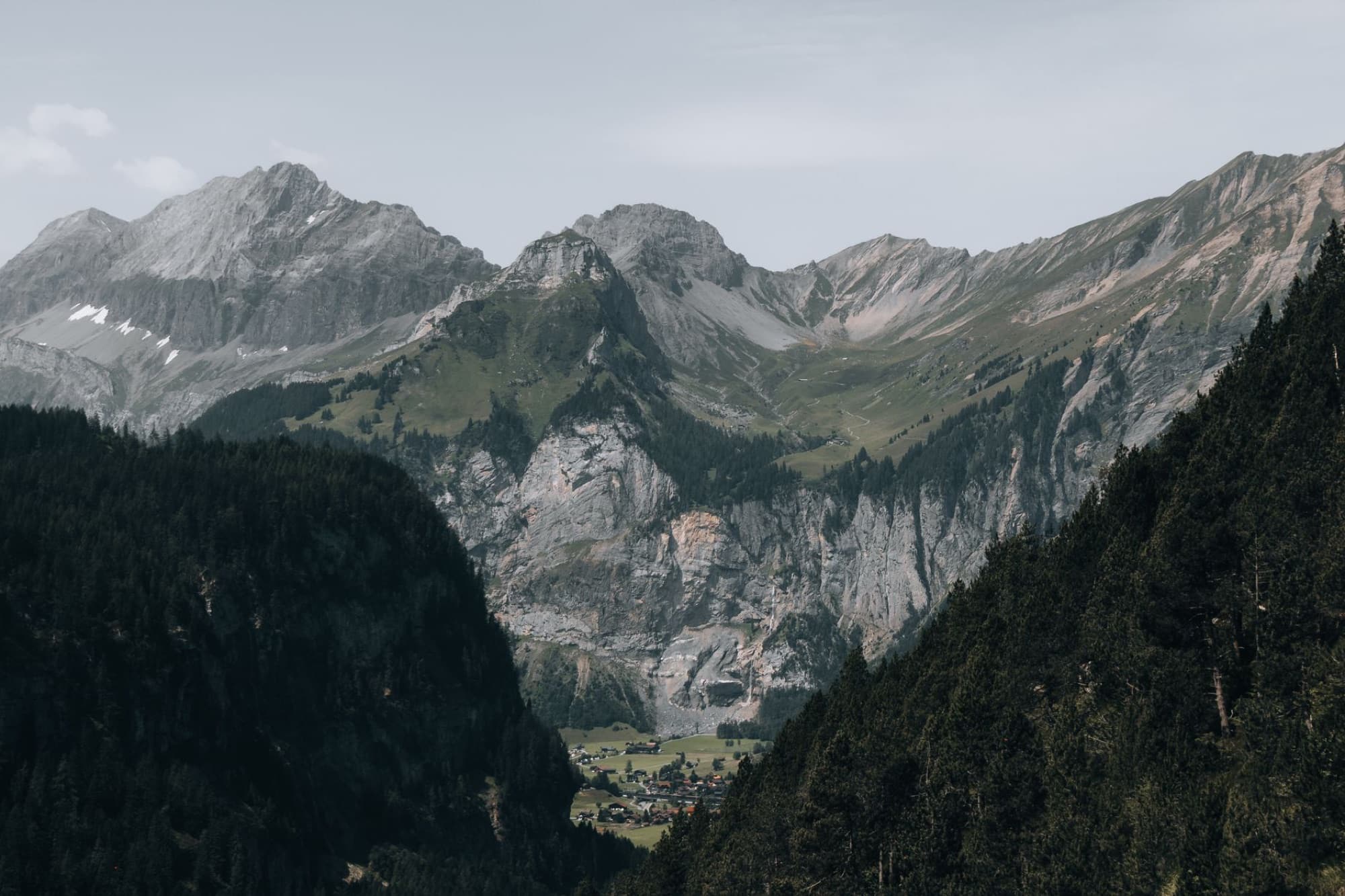A picturesque mountain village nestled in a lush alpine valley surrounded by rocky peaks.