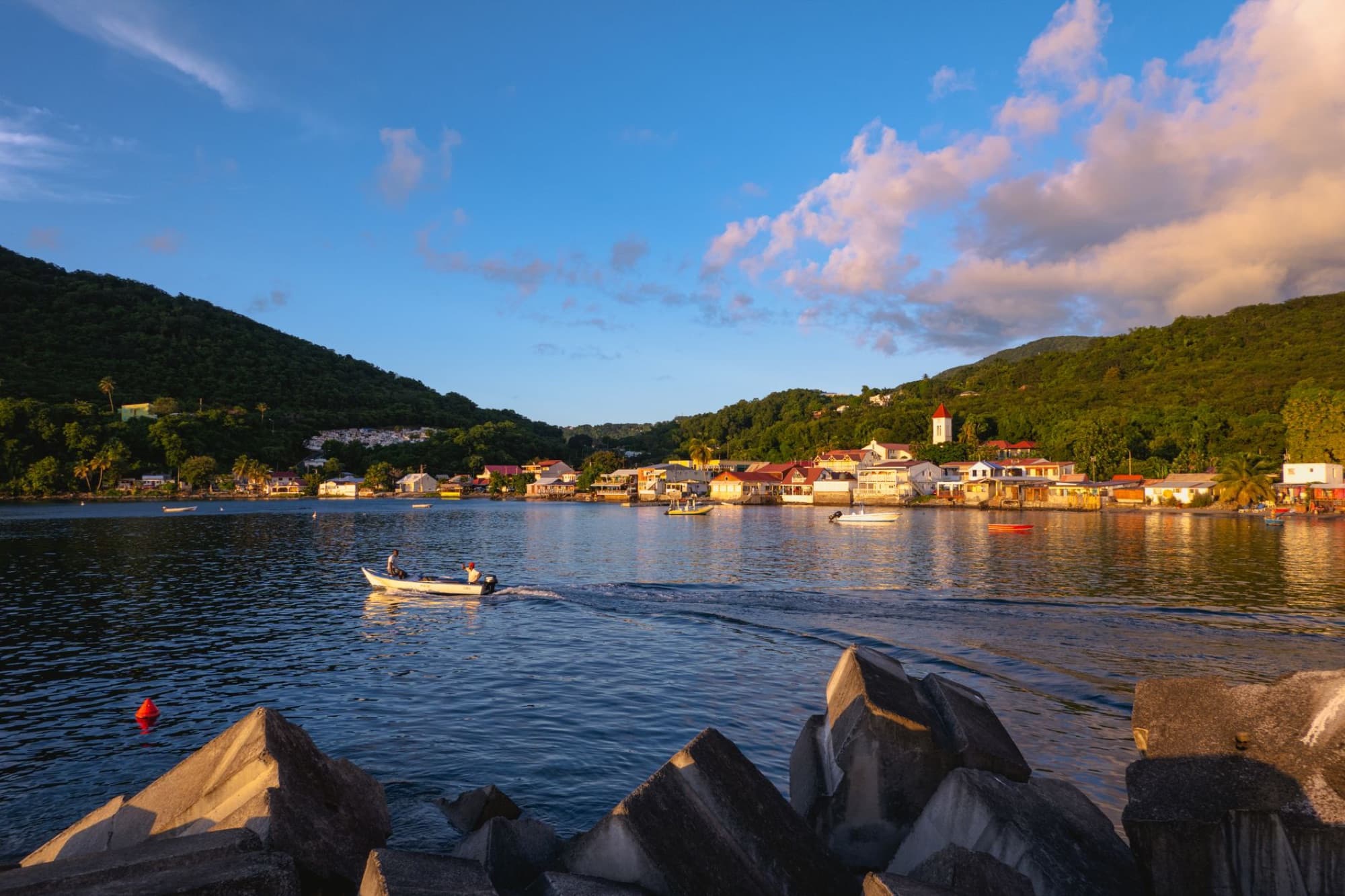A picturesque sunset over Deshaies Bay, Guadeloupe, with a small boat in the foreground.