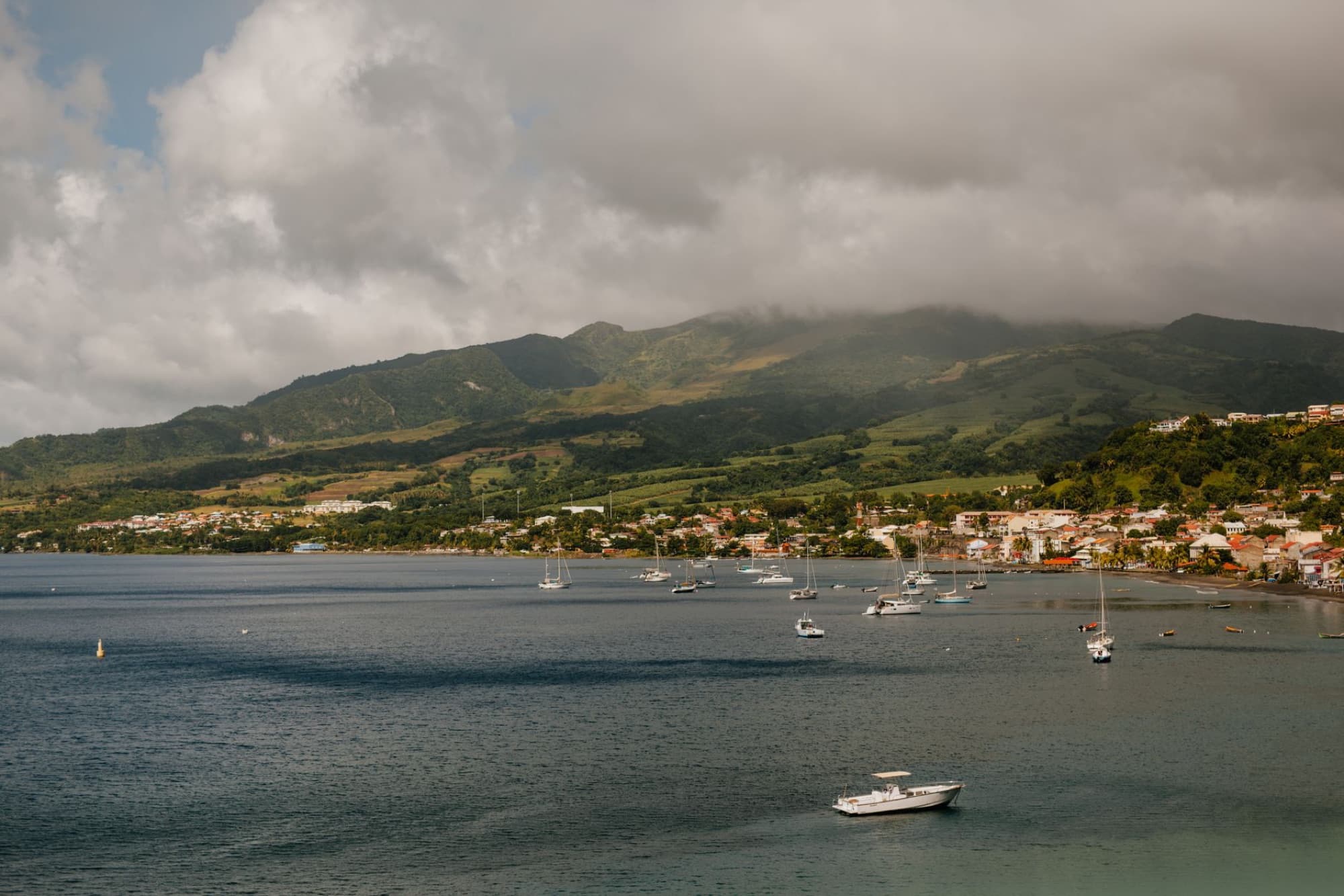 Scenic view of a coastal town nestled between mountains and sea, with boats on tranquil waters.