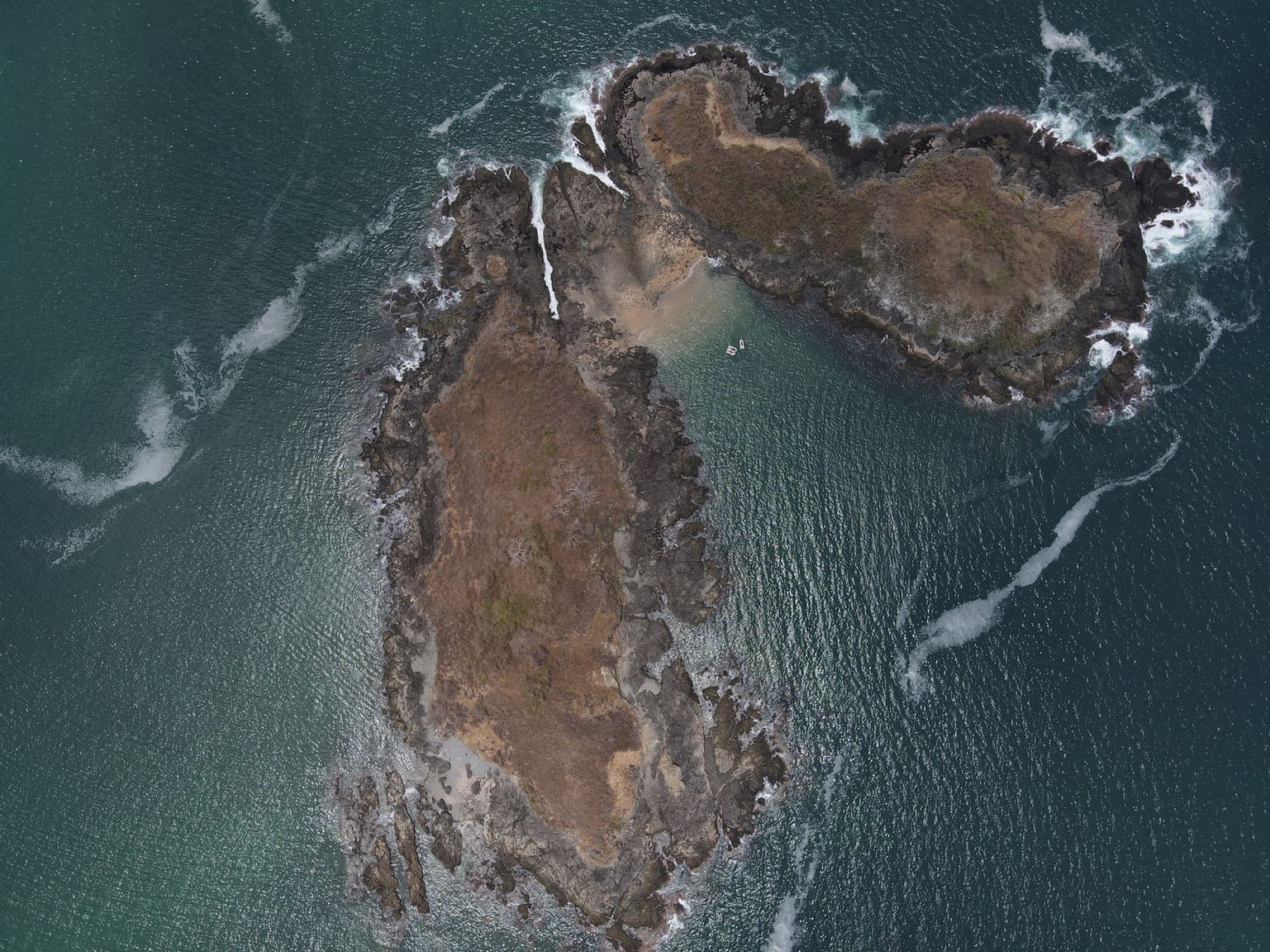 Drone aerial view of rocky islands and green water in Guanacaste, Costa Rica.