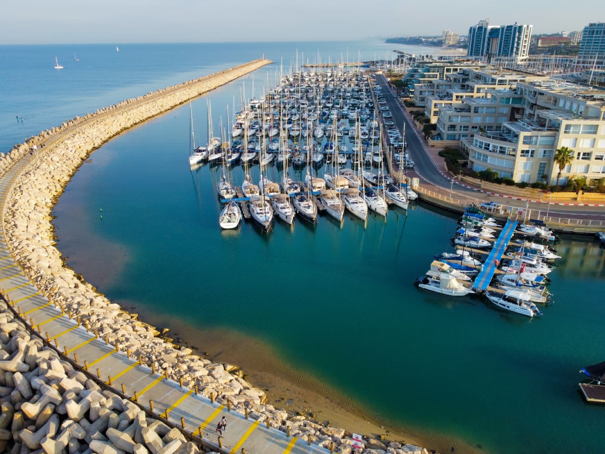 Stunning aerial shot of Herzliya Marina showcasing yachts docked in the harbor against the Mediterranean Sea.