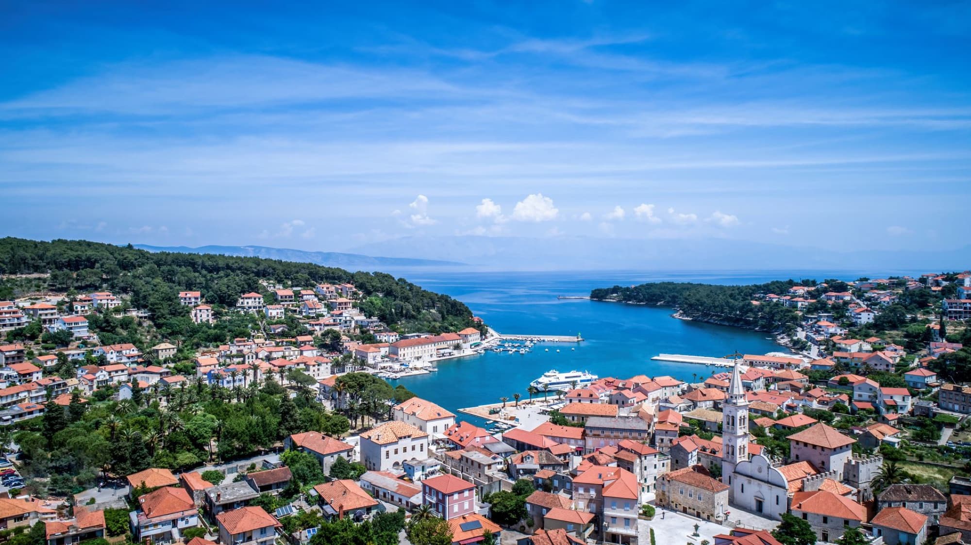 Scenic aerial view of Hvar, Croatia, with vibrant rooftops and blue Adriatic Sea under a clear sky.