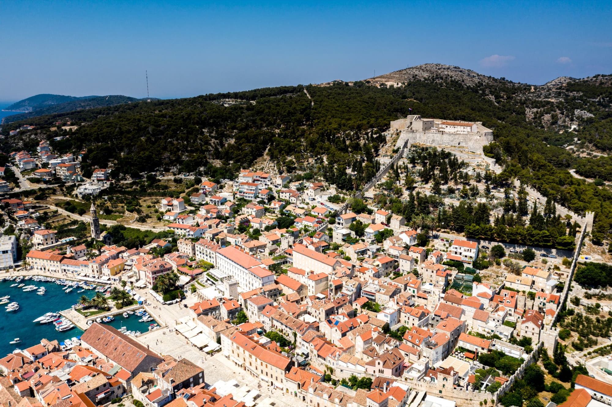 Discover Hvar's scenic coastal town from above, showcasing historical architecture and lush landscapes.