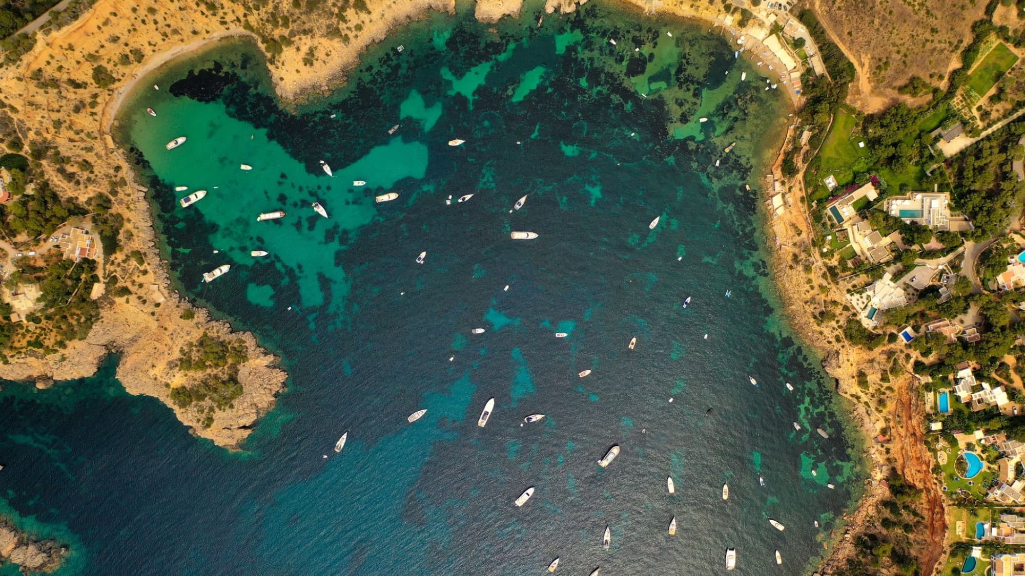Stunning aerial view of Ibiza's coastline with boats and clear waters.