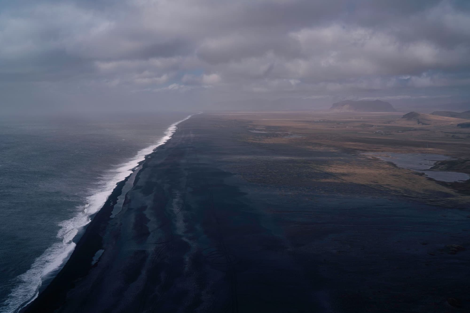 A breathtaking aerial view of a dramatic Icelandic coastline under a cloudy sky, showcasing natural beauty.