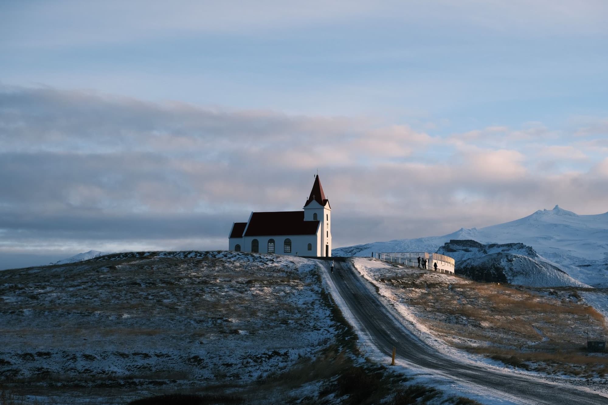 Beautiful Icelandic church on a hill at sunset in winter, showcasing serene landscape.