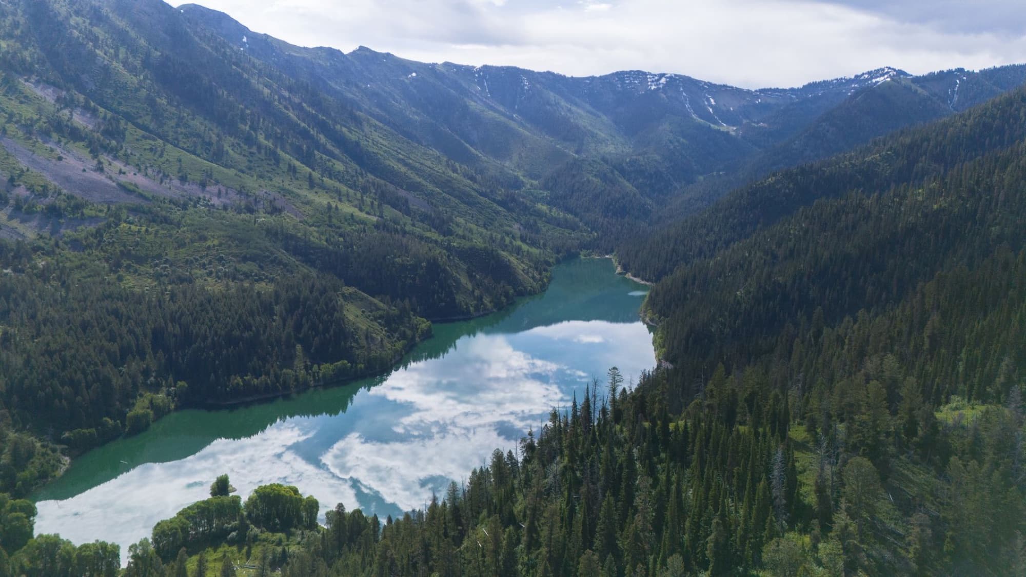 A breathtaking aerial view of a serene lake nestled between lush mountains in Irwin, Idaho.