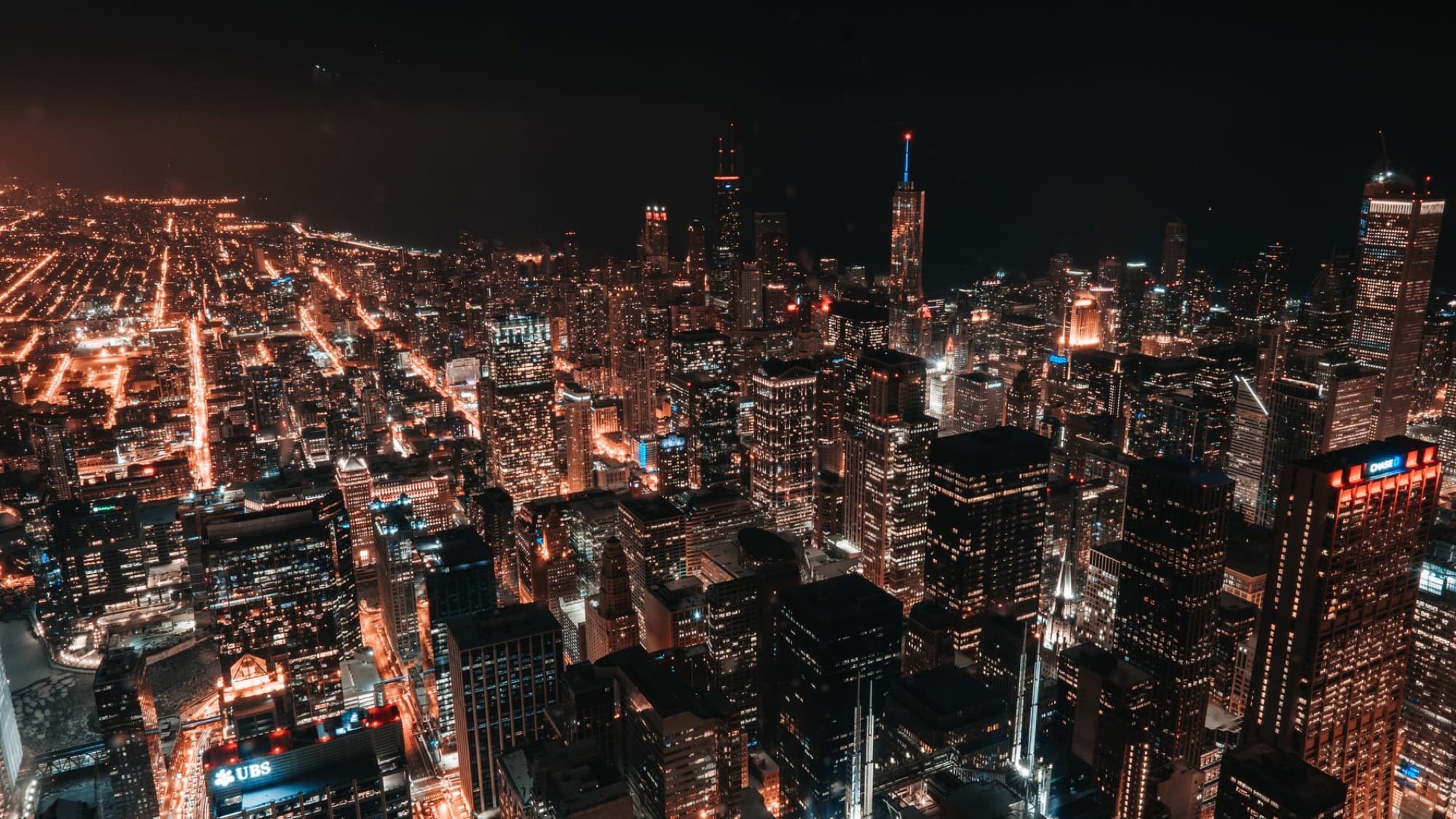 Aerial night view of Chicago's illuminated skyline showcasing skyscrapers and city lights.