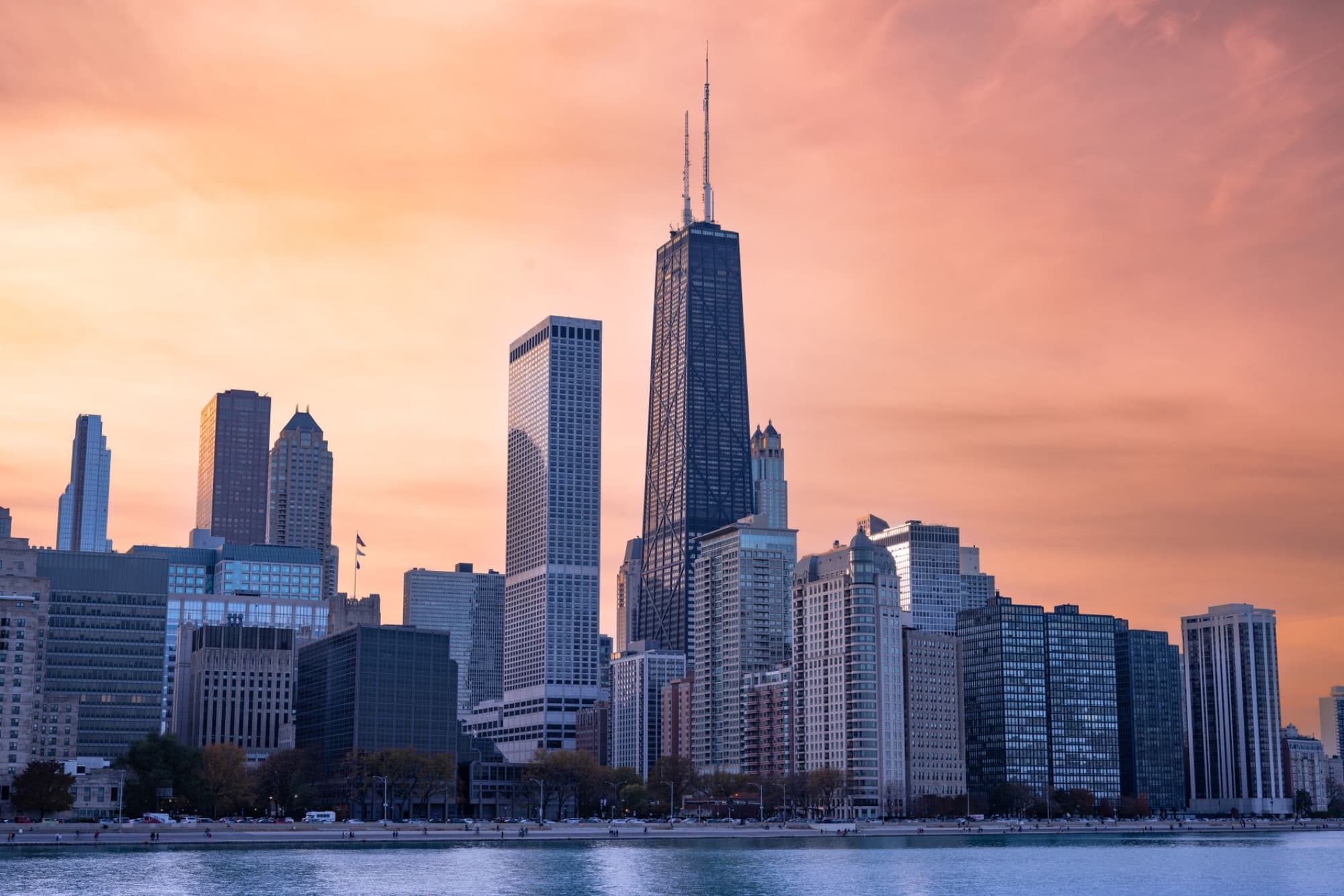Breathtaking view of Chicago's skyline at sunset with iconic skyscrapers reflecting on the waterfront.