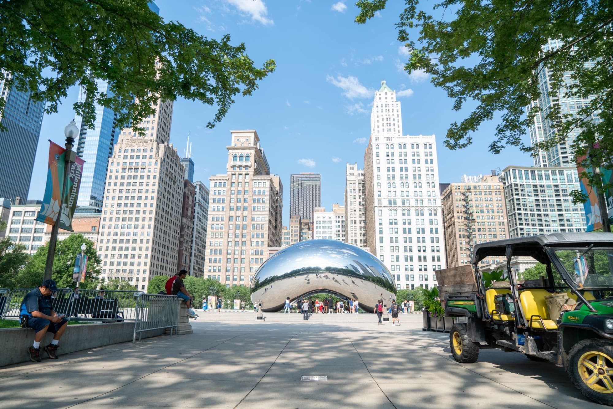 Cloud Gate sculpture in Chicago's Millennium Park with city skyline on a sunny day.