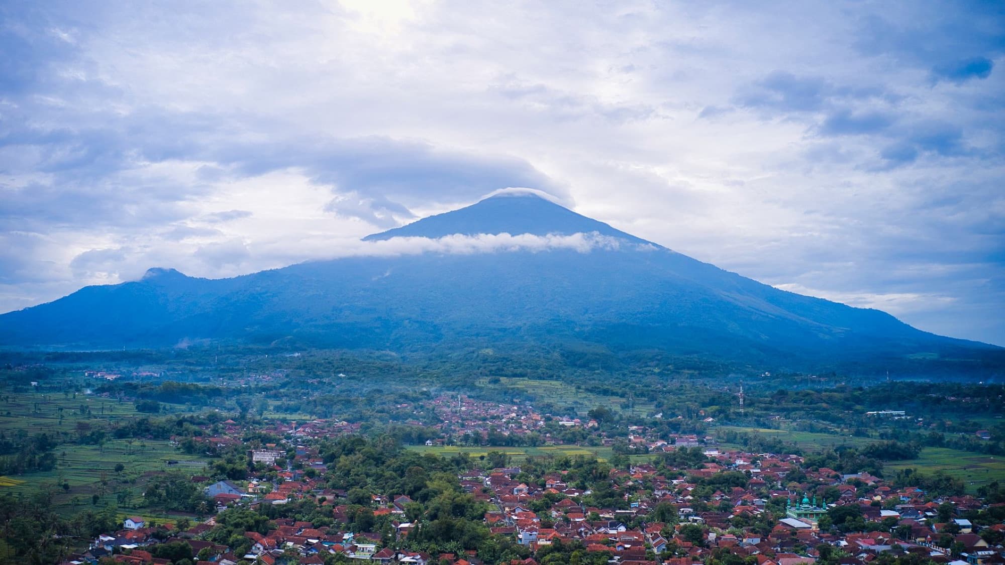 Stunning aerial view of Mount Salak with a village nestled below, captured in West Java, Indonesia.